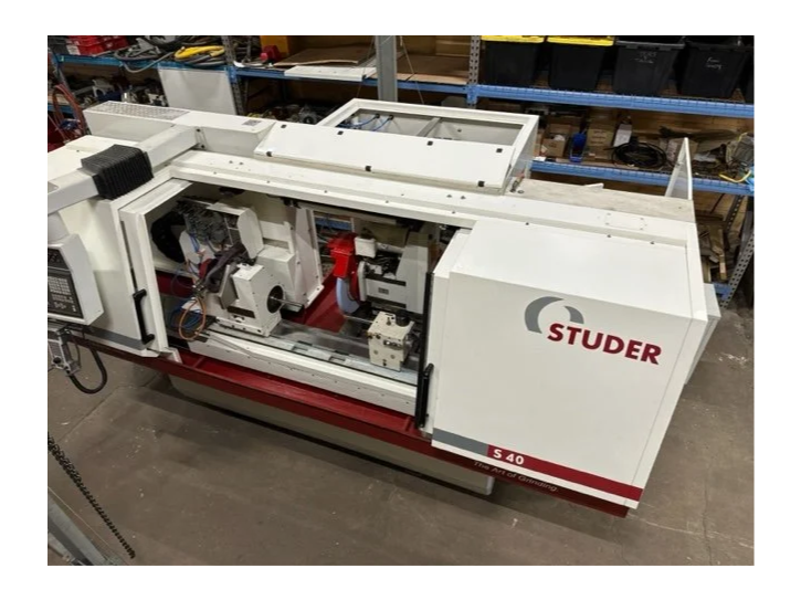 A Studer S 40 CNC grinding machine in a workshop, with shelves and tools in the background.