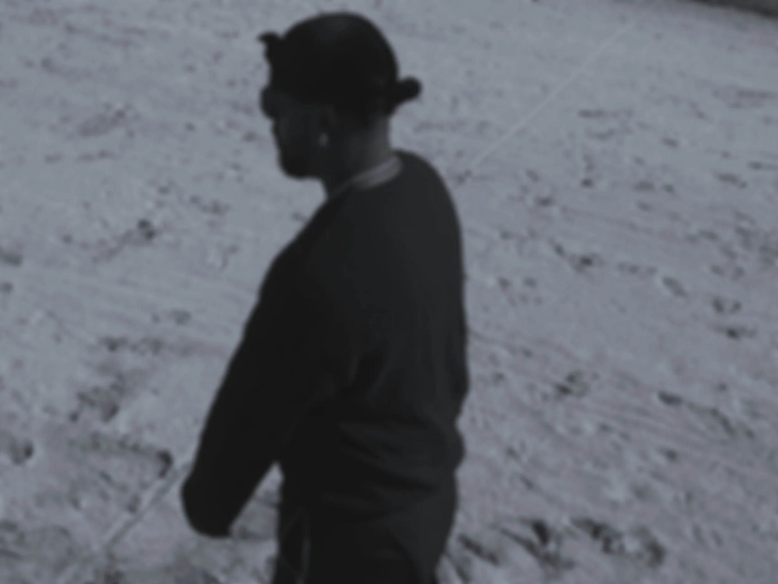 A silhouette of a person wearing a cap and glasses, walking on a snow-covered ground at night.