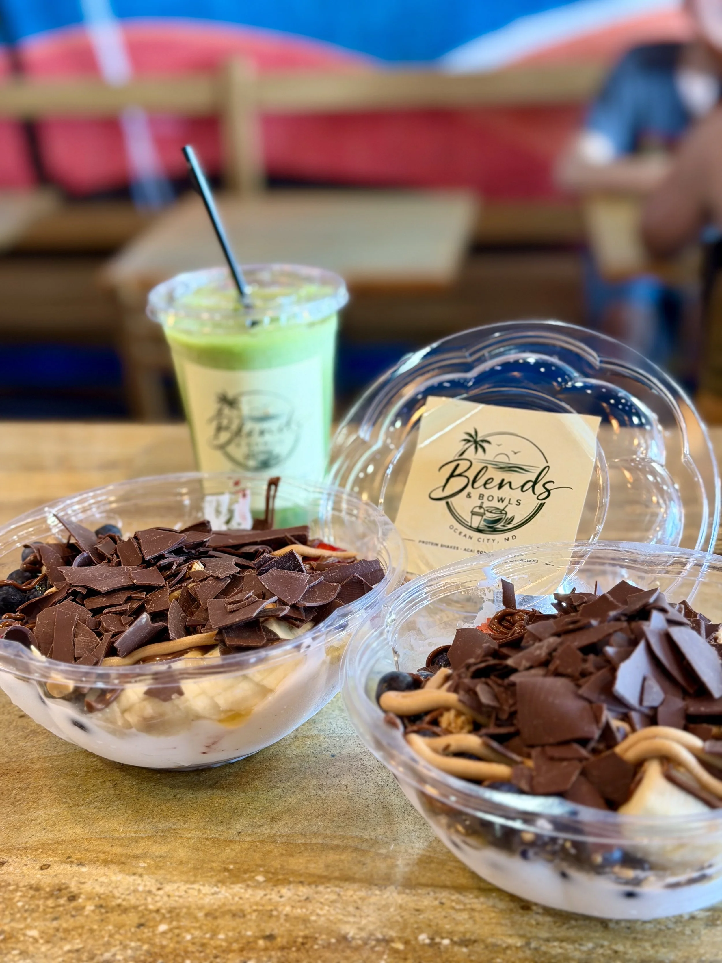 Three bowls of dessert topped with chocolate shavings on a wooden table at a restaurant named Blends & Bowls in Ocean City, Maryland.