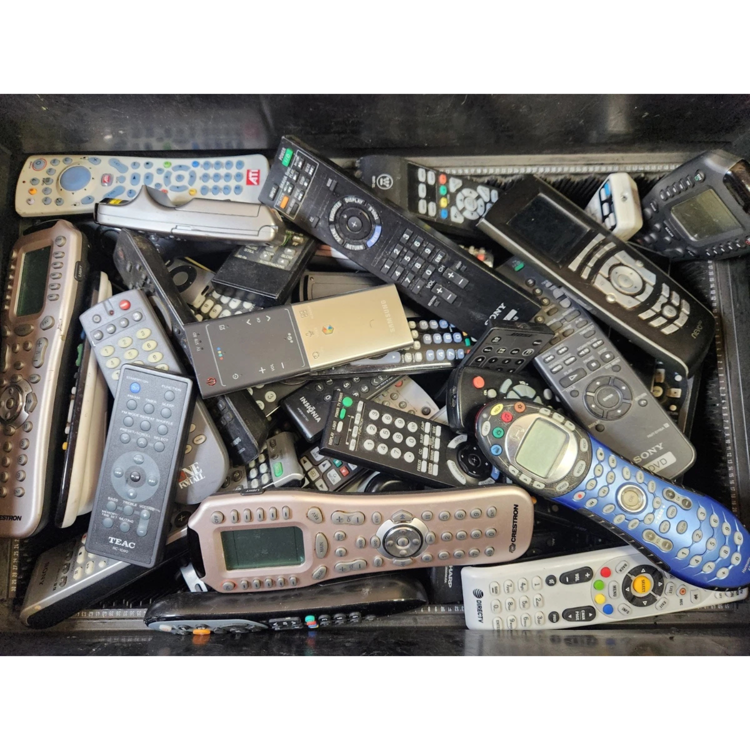 A collection of various remote controls piled together in a box.