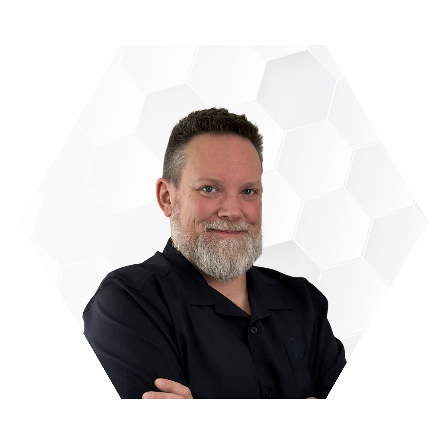 A man with short dark hair, a full beard, and a pleasant expression, wearing a black shirt with arms crossed, in front of a white background with a hexagonal pattern.