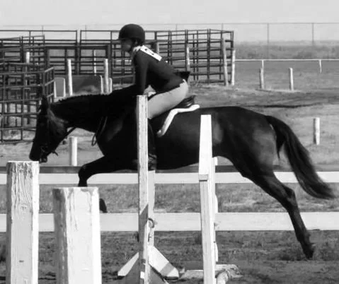 A person riding a horse during a jump in an equestrian event.