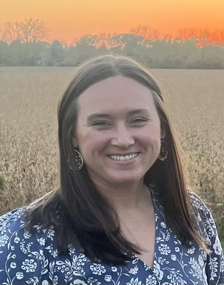 Erin Wolski headshot in front of a field with sunset behind her