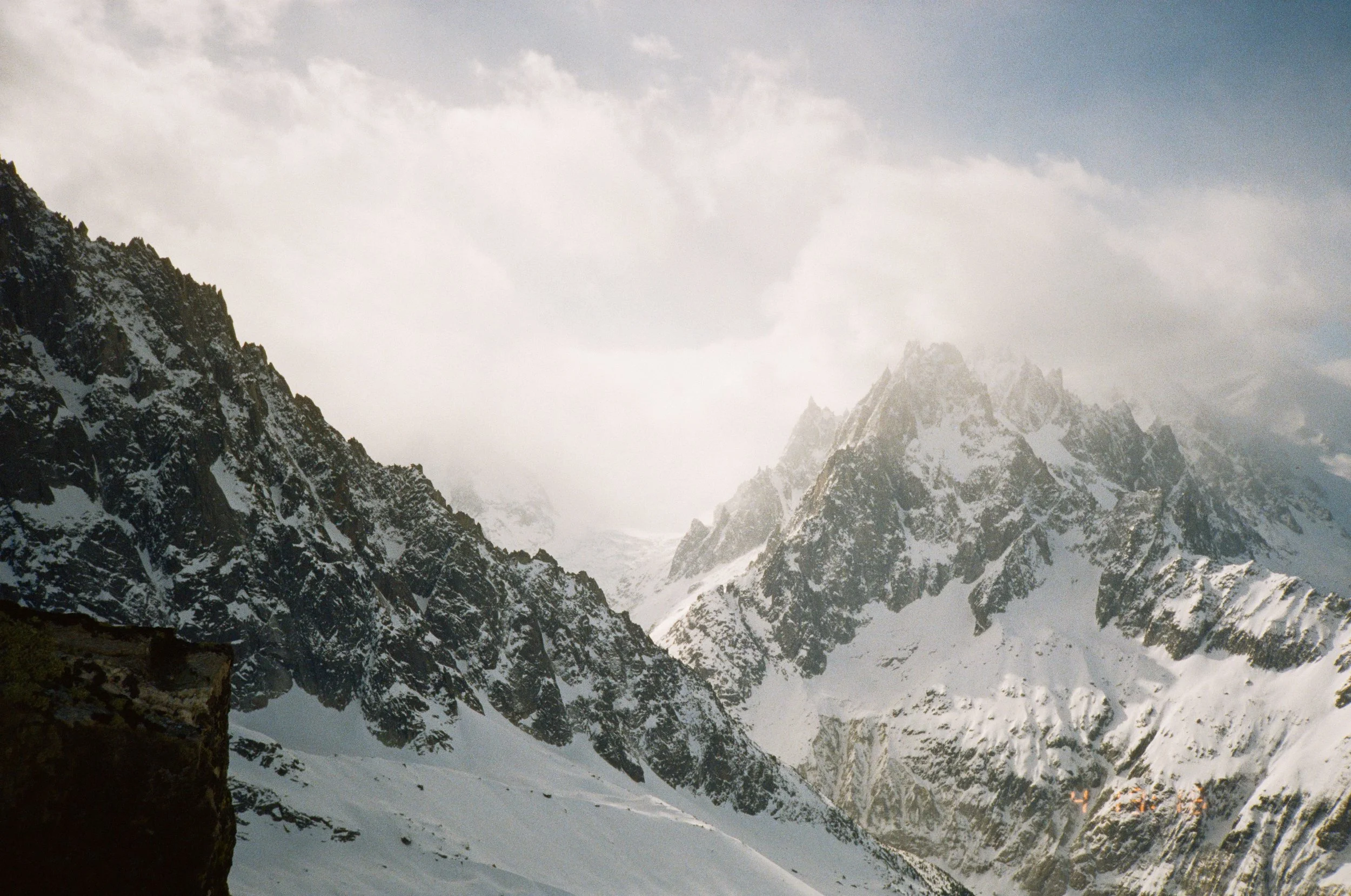 Snow-covered mountain peaks with a cloudy sky.