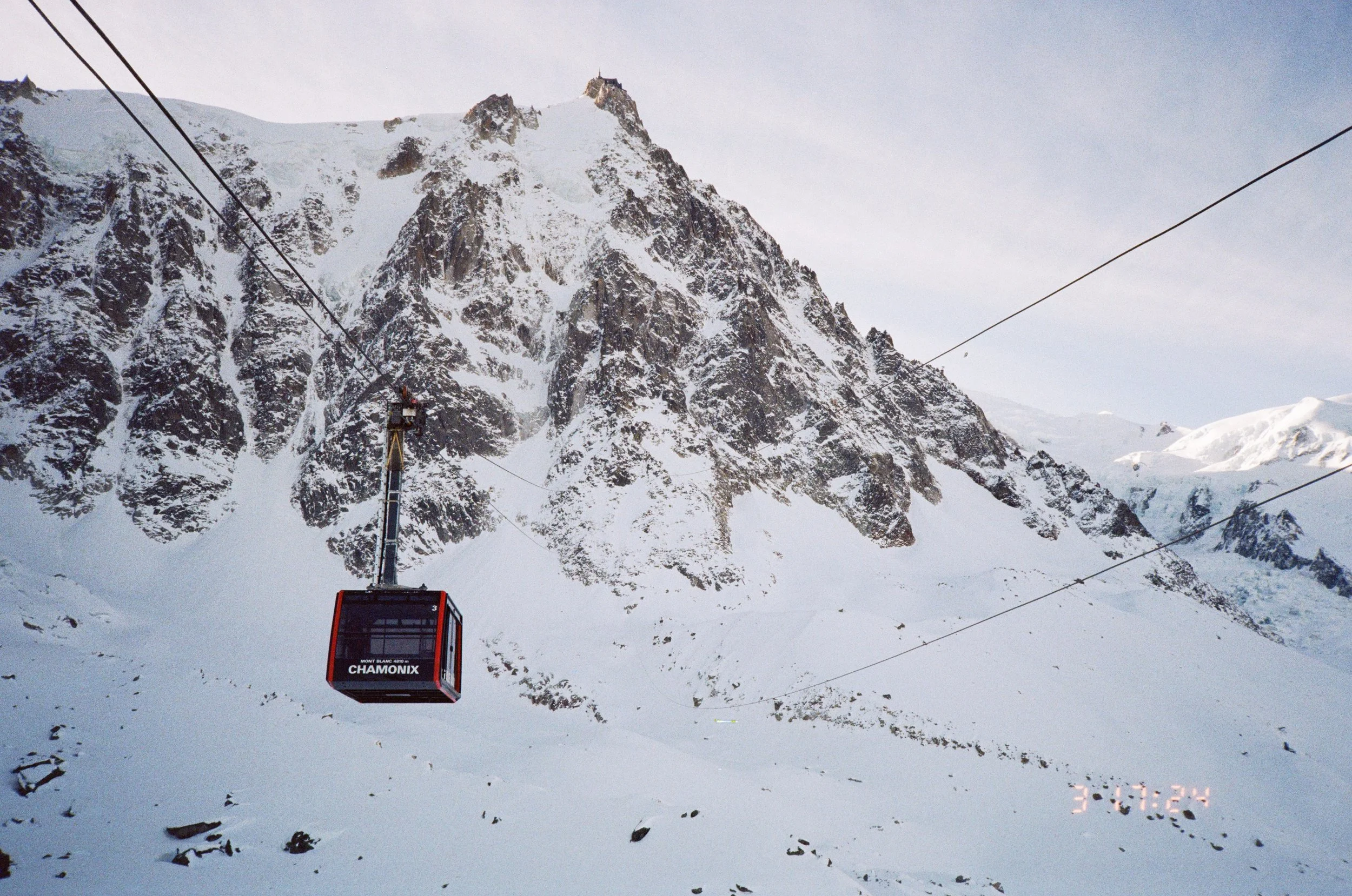 A cable car suspended in front of a snow-covered mountain in Chamonix, France.