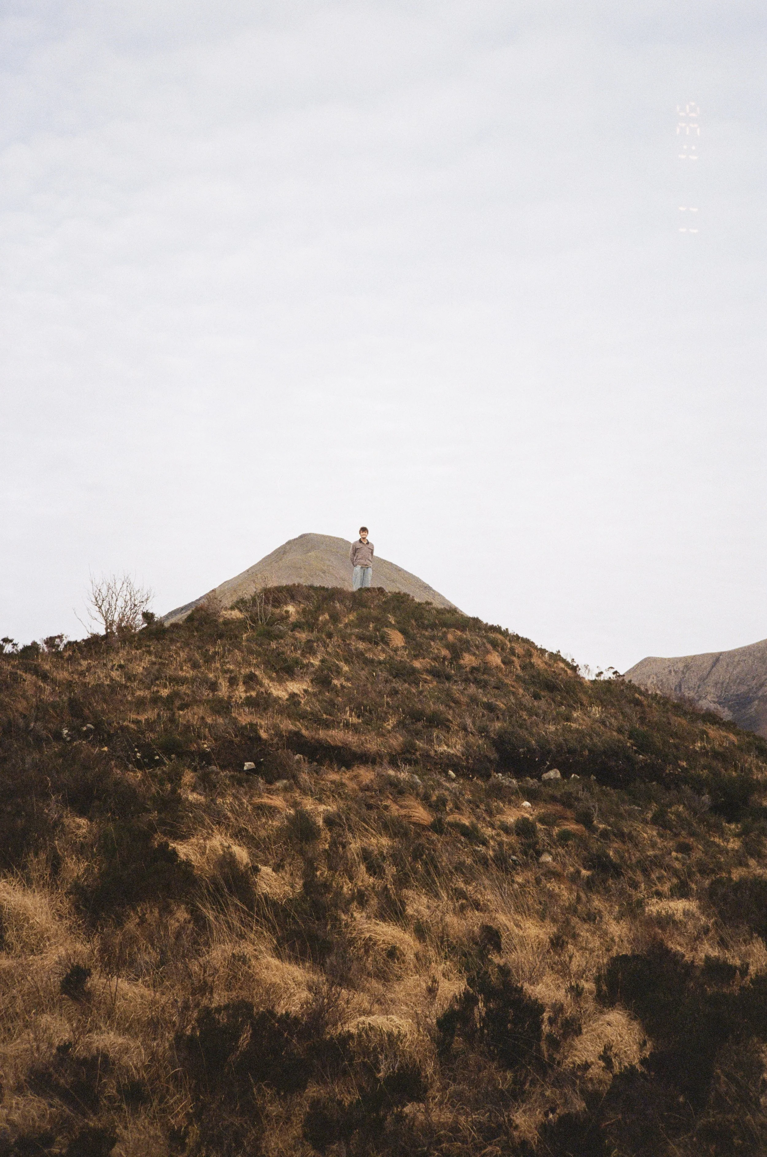 Person standing on a hilltop in a mountainous landscape during daytime.