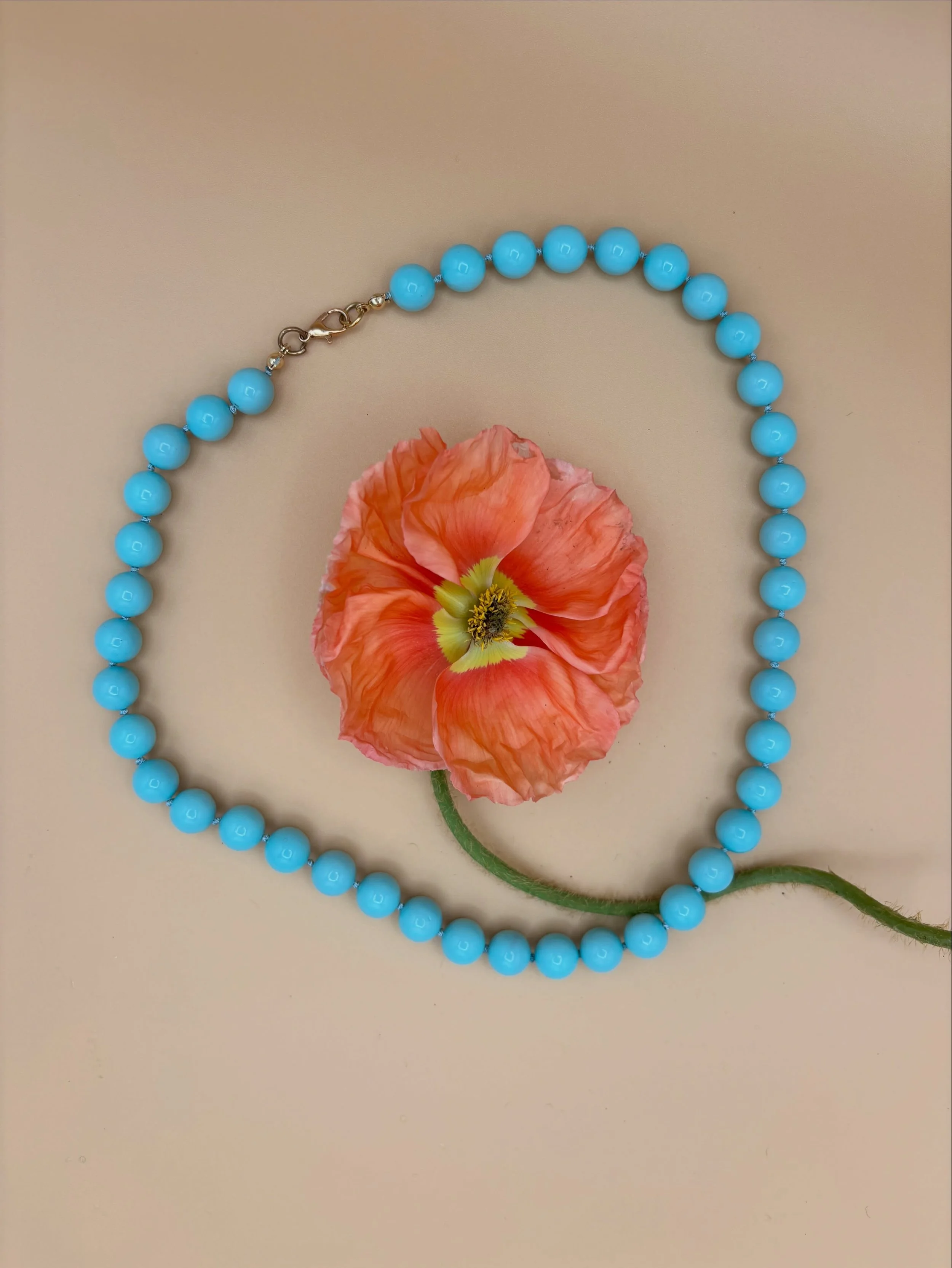 Shell pearls. A mother of pearl centre wrapped in layers on layers of crushed pearl and lustrous lacquer to form a flawless bead that has the weight and feel of natural pearls but is more durable, and comes in fun colours like this aqua blue. 

Hand 