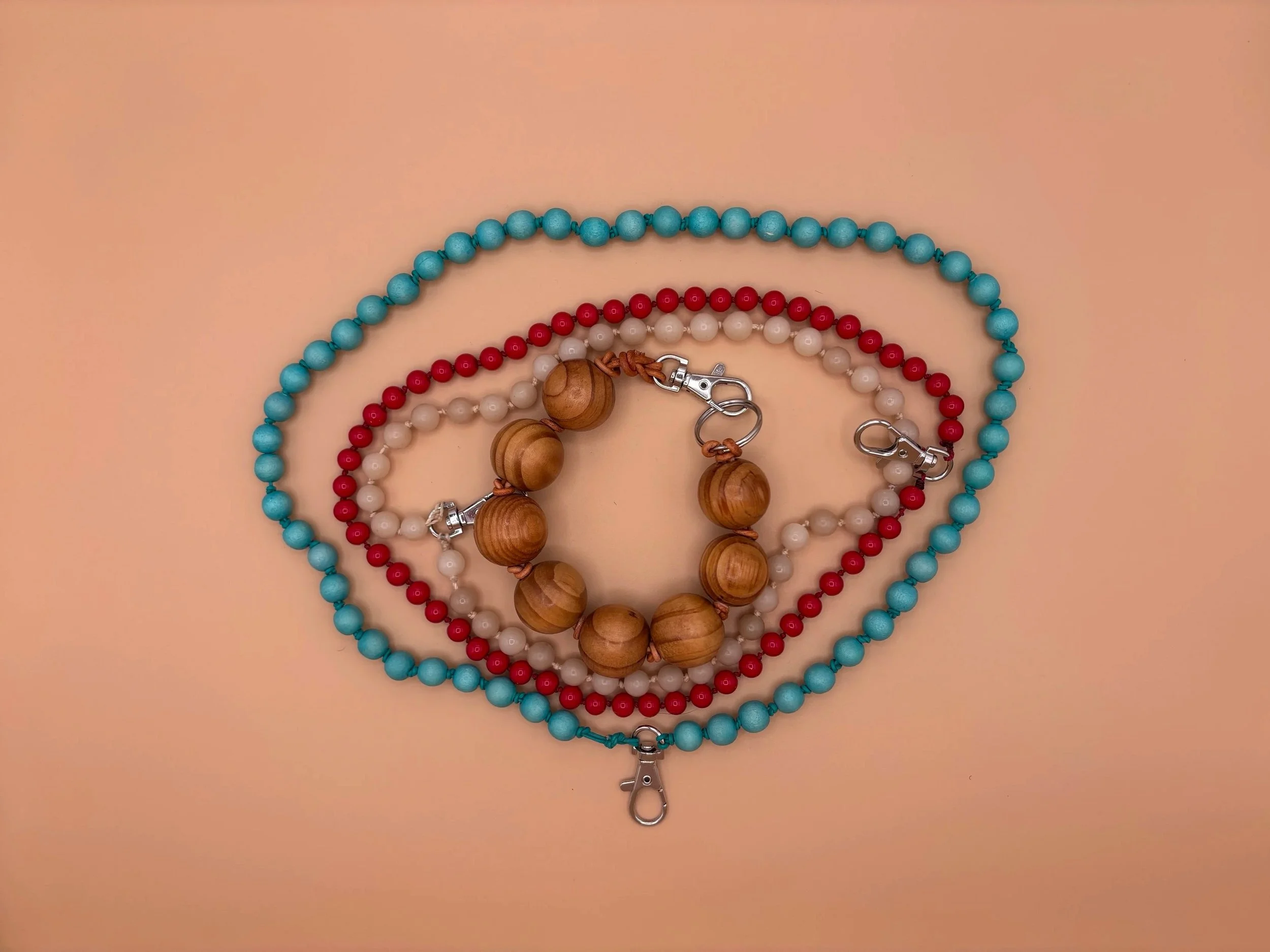 Colorful beaded necklaces with wooden and metal clasps arranged on a beige surface.