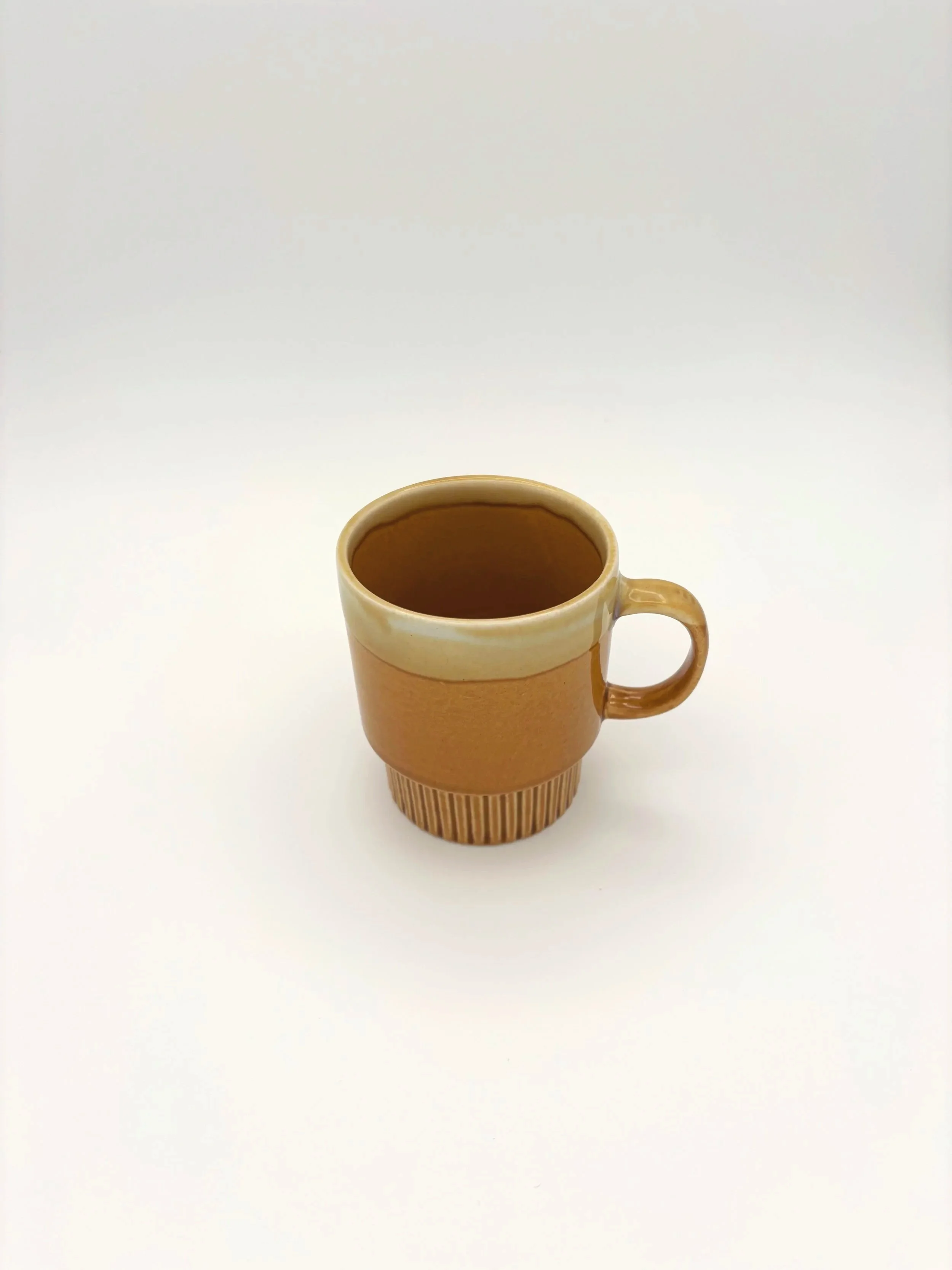 A beige ceramic mug filled with coffee, placed on a round wooden coaster on a white surface with a plain white background.