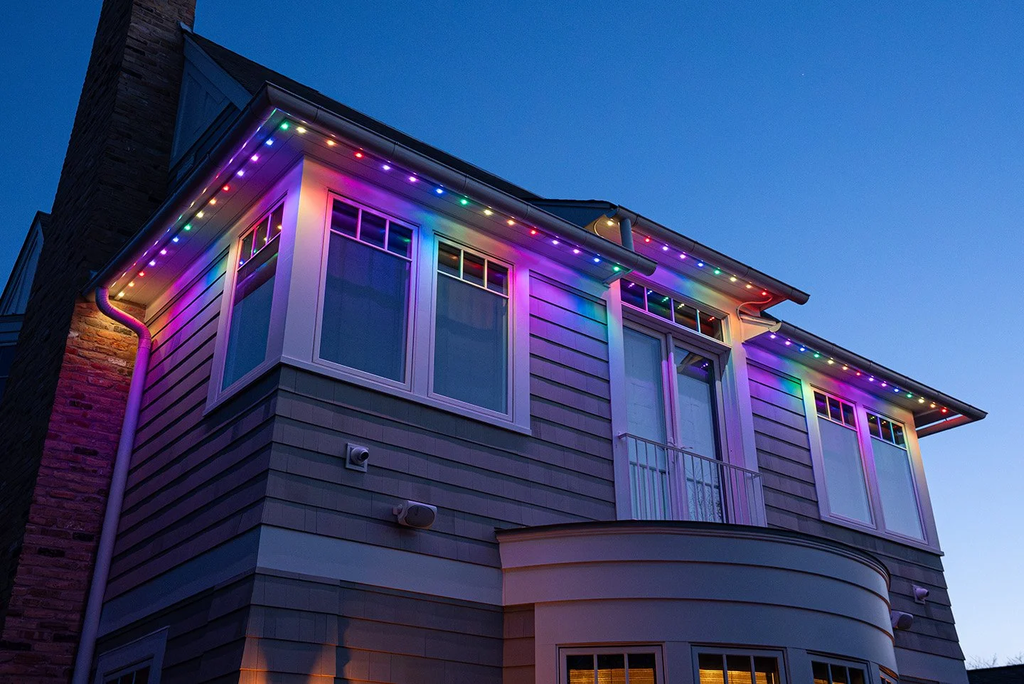 Decorated Christmas trees with string lights framing a black door with a brick wall background.