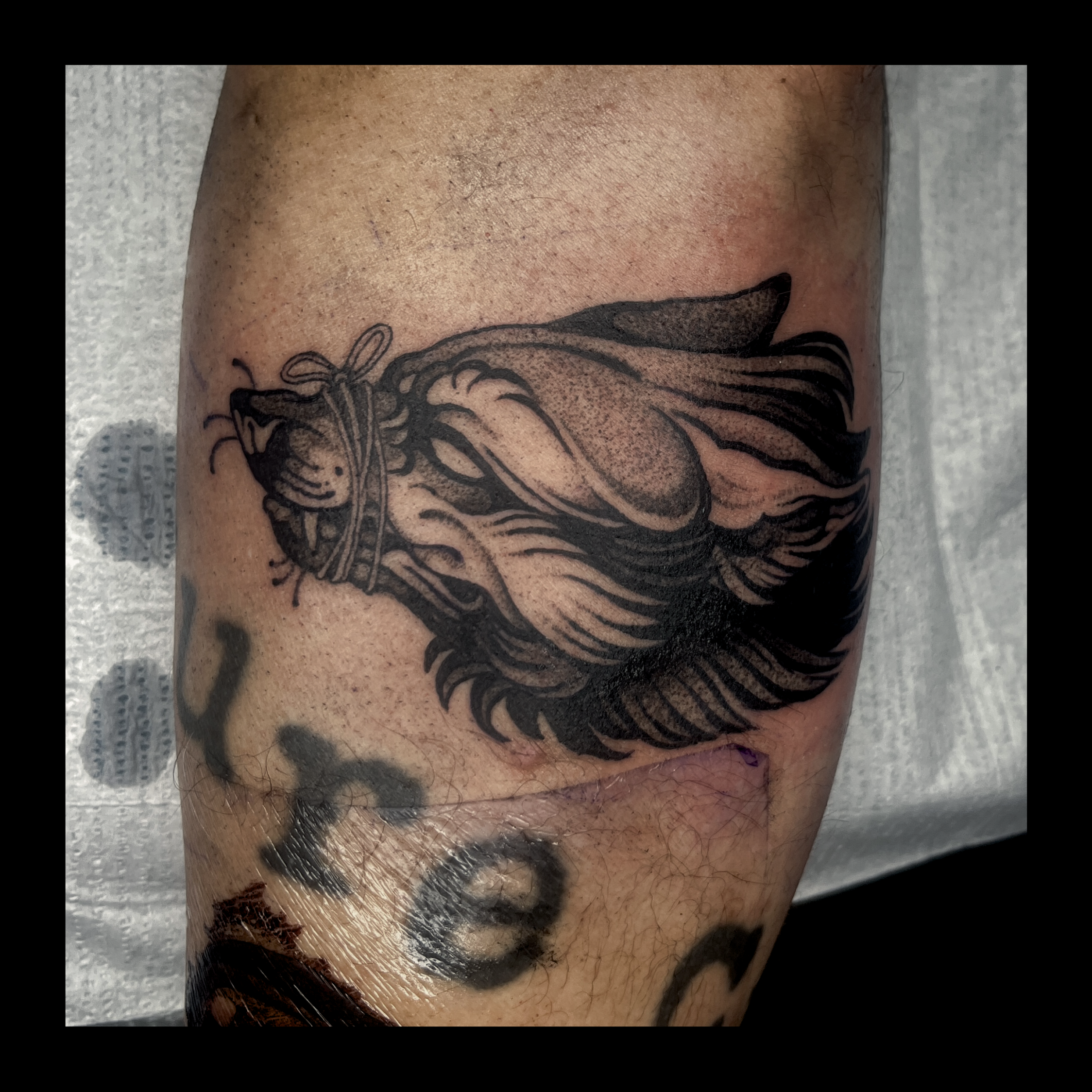 Close-up of a tattoo of a lion's head on a person's arm.