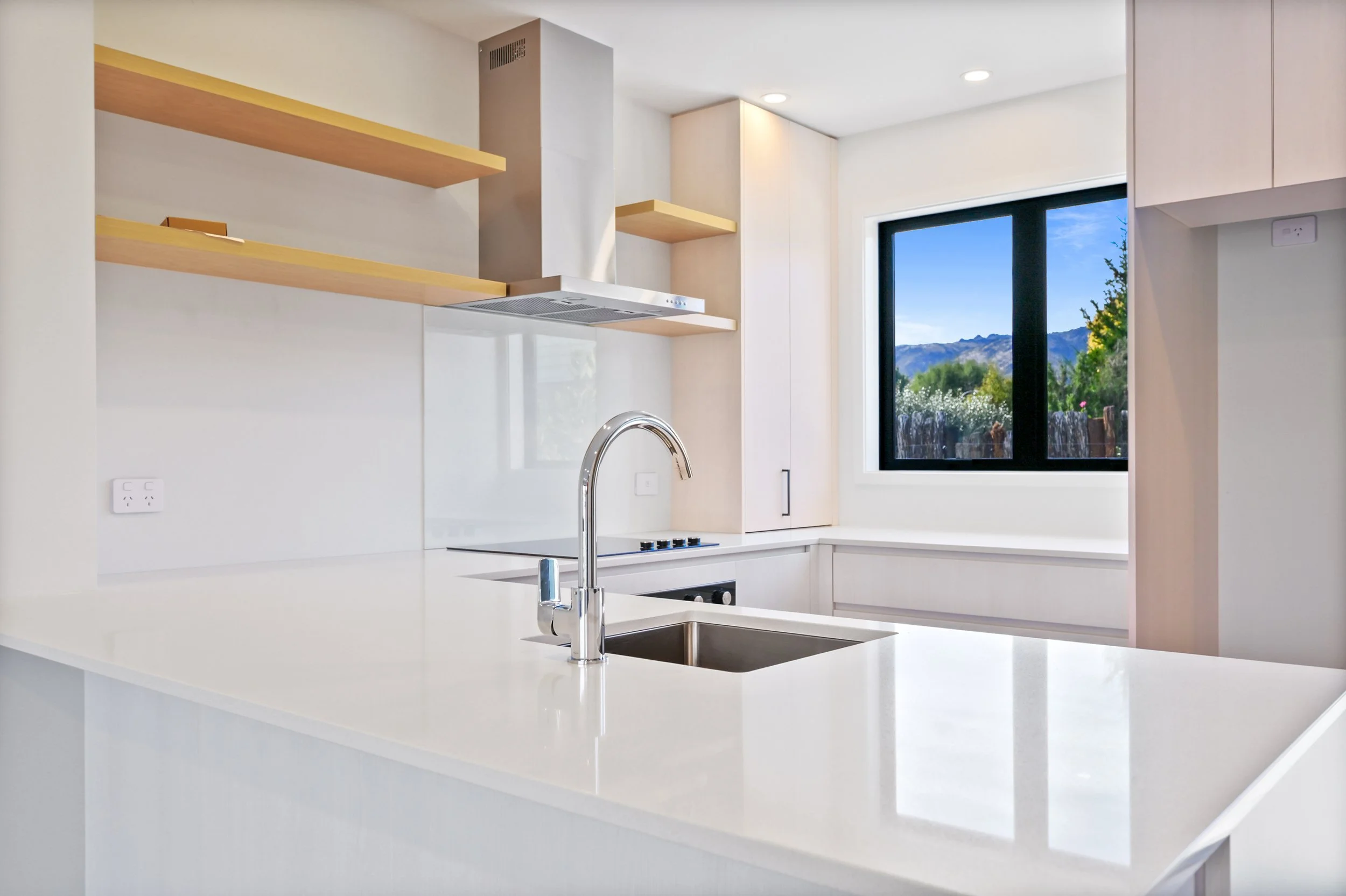Modern kitchen featuring quality appliances, ample cabinetry and a bright open-plan design with mountain views beyond.