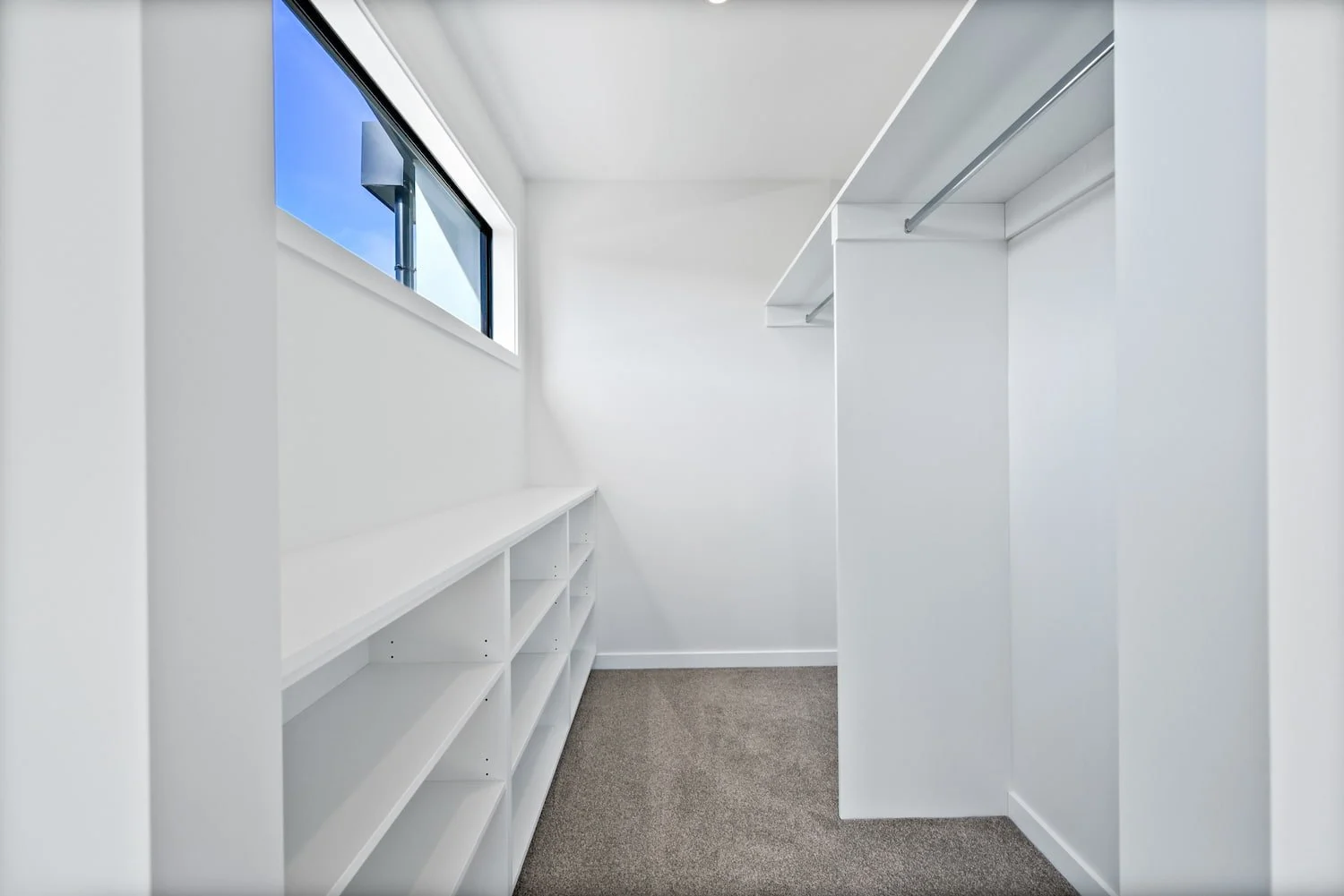 Spacious walk-in wardrobe in a Pisa Vistas townhouse, with built-in shelving, hanging rail and carpeted flooring.