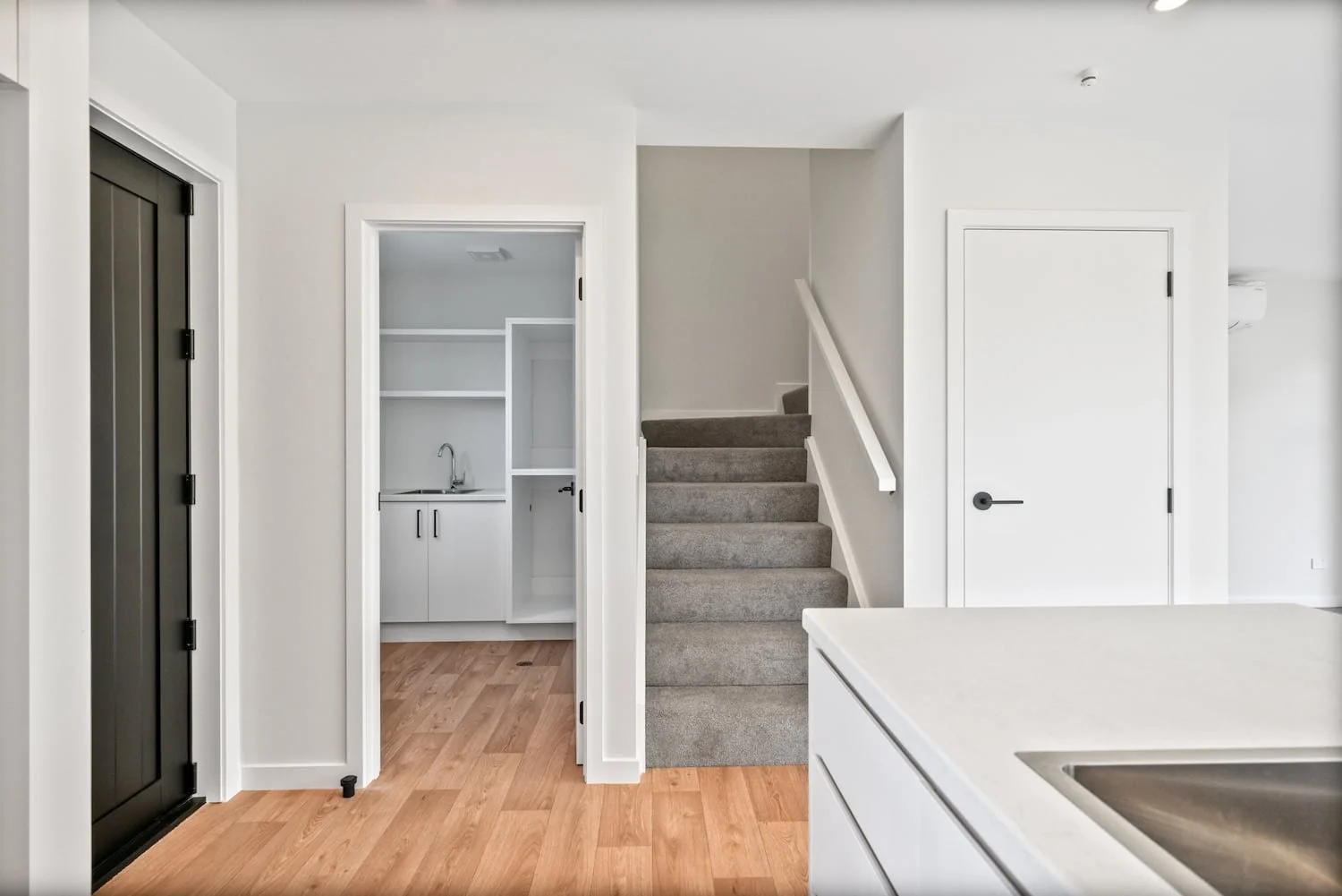 Hallway and dedicated laundry room in a Pisa Vistas townhouse, with built-in shelving, cabinetry and timber flooring.