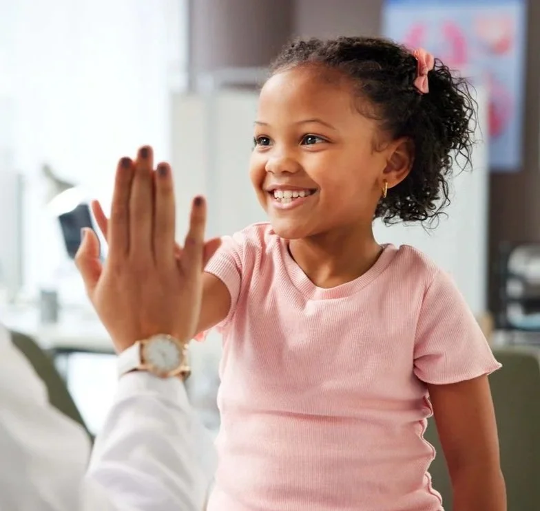 A young girl with curly hair and a pink shirt giving a high five to her speech therapist for kids in Whitmore Lake, MI.