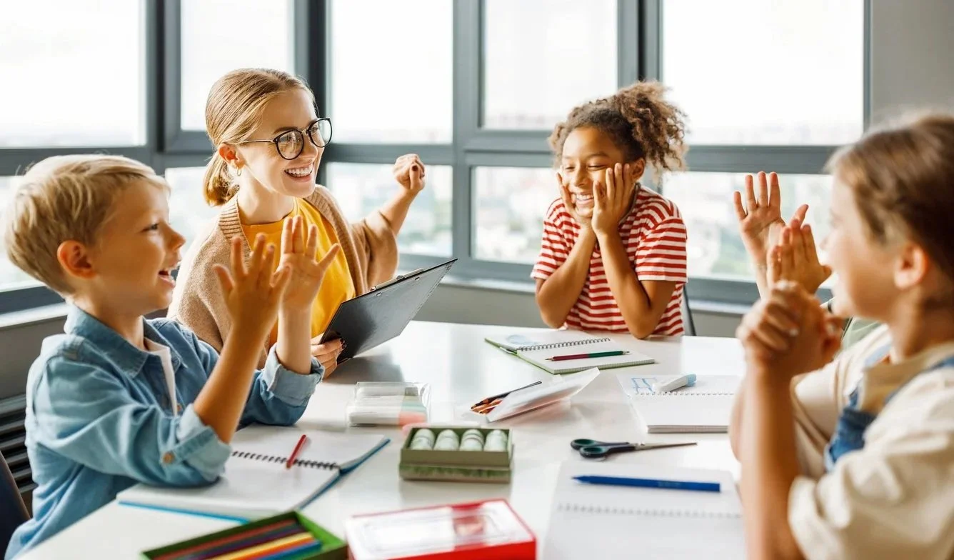 Children will improved communication skills after working with a school contract speech therapist in Michigan, all sitting at a table filled with notebooks, pencils, and art supplies.