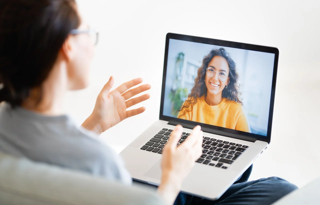 An adult male is having a video call on a laptop with a speech therapist who is helping him with clearer speech after stroke during online speech therapy for adults in Michigan.