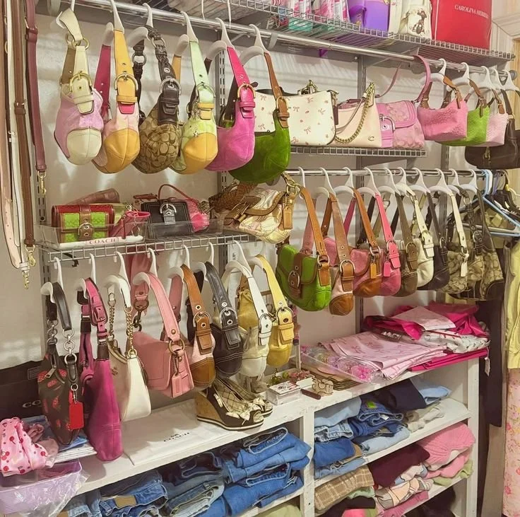 Display of various handbags in different colors and styles on shelves, along with folded clothes and accessories.