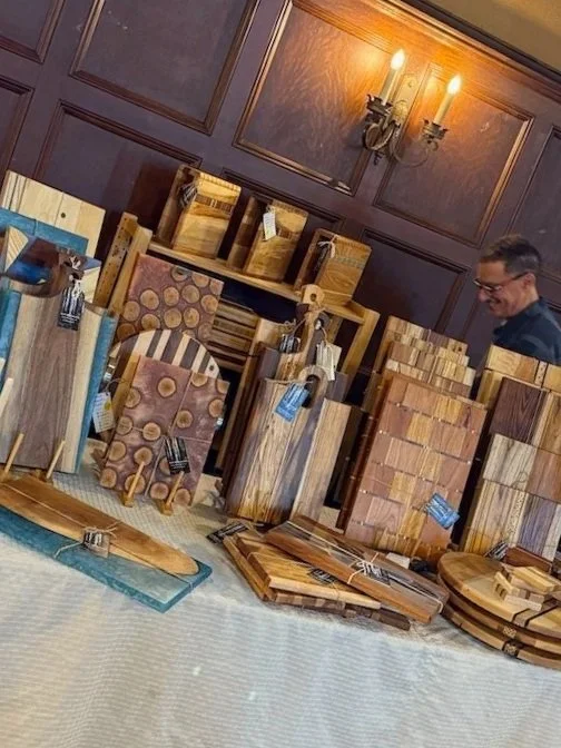 Différents planches et blocs de bois pour la fabrication ou la décoration, exposés sur une table dans une pièce avec murs en bois et lampes murales