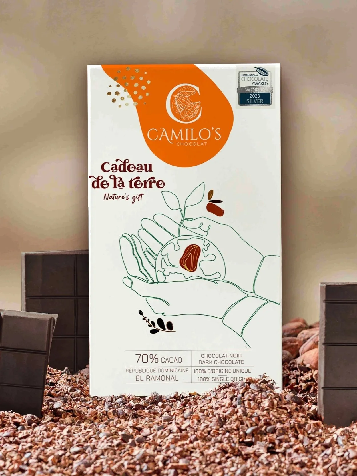 Boîte de chocolat noir de la marque Camilo's, qualité cacao 70%, origine République Dominicaine, emballage blanc avec dessin d'une main tenant une graine de cacao et écritures en français et anglais. Un sticker indique une récompense d'argent en 2023 aux International Chocolate Awards.