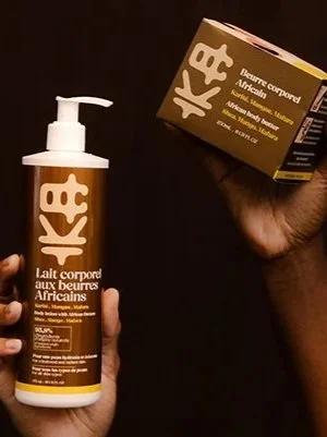 Une main tient un flacon de lait corporel aux beurres africains et une autre main tient une boîte avec la même inscription.