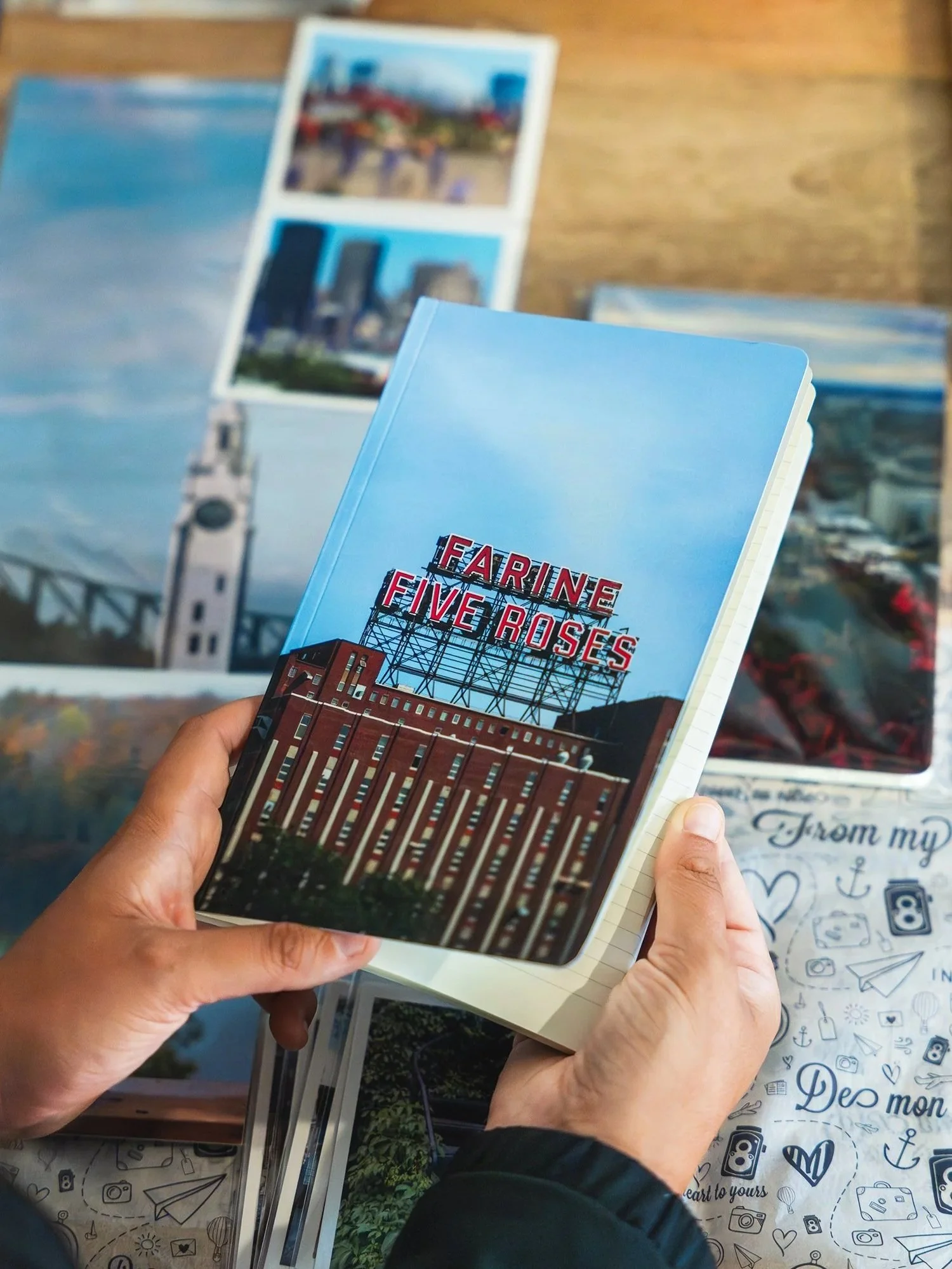 Livre touristique intitulé 'Faring Five Roses' avec une image de bâtiment industriel, une personne tient le livre, d'autres images de carte postale sont visibles en arrière-plan.