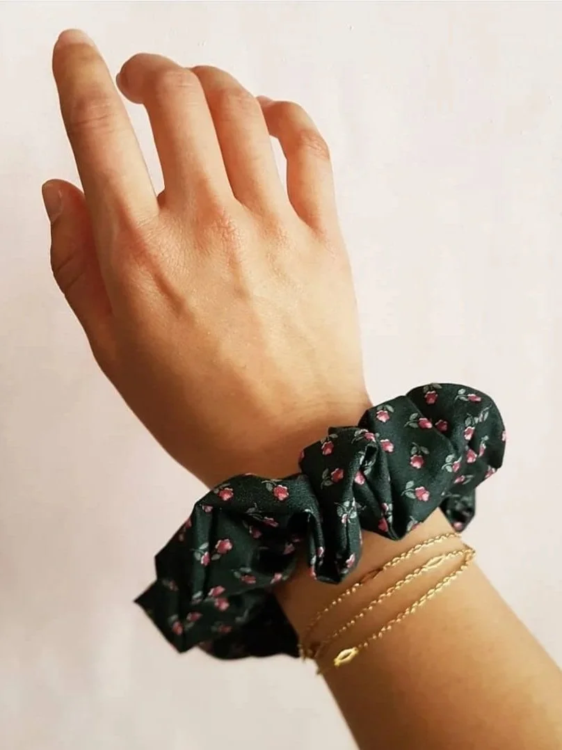 Main avec un bracelet en tissu à fleurs et deux bracelets fins en or.