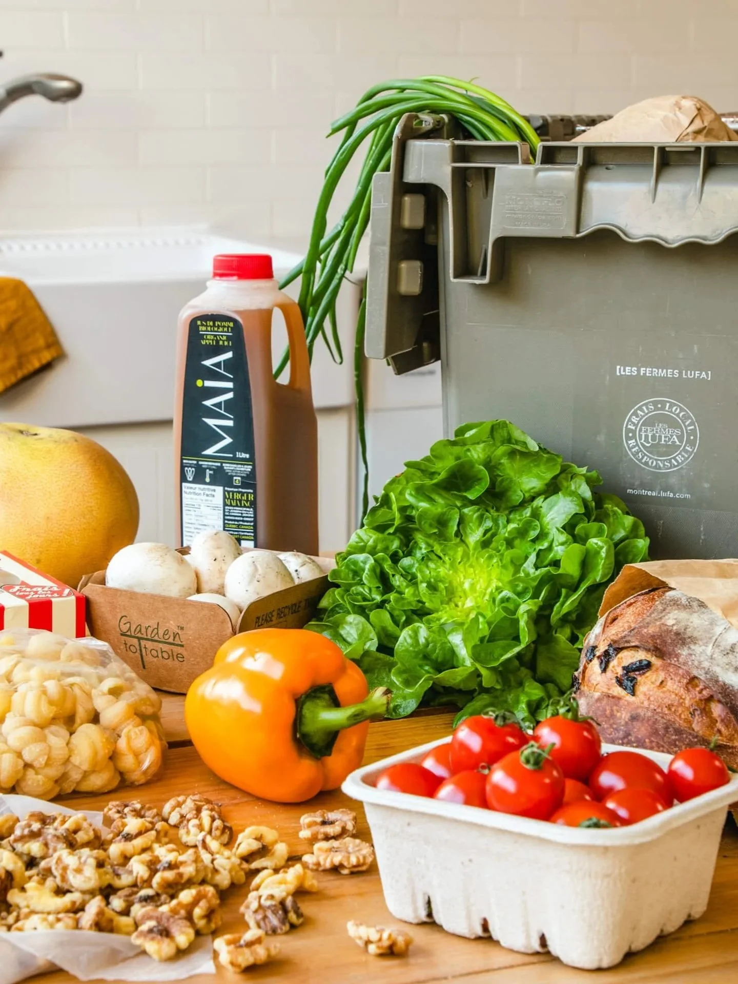 Une sélection de légumes frais, fruits, et aliments, avec une boîte en carton verte pour déchets organiques, dans une cuisine.
