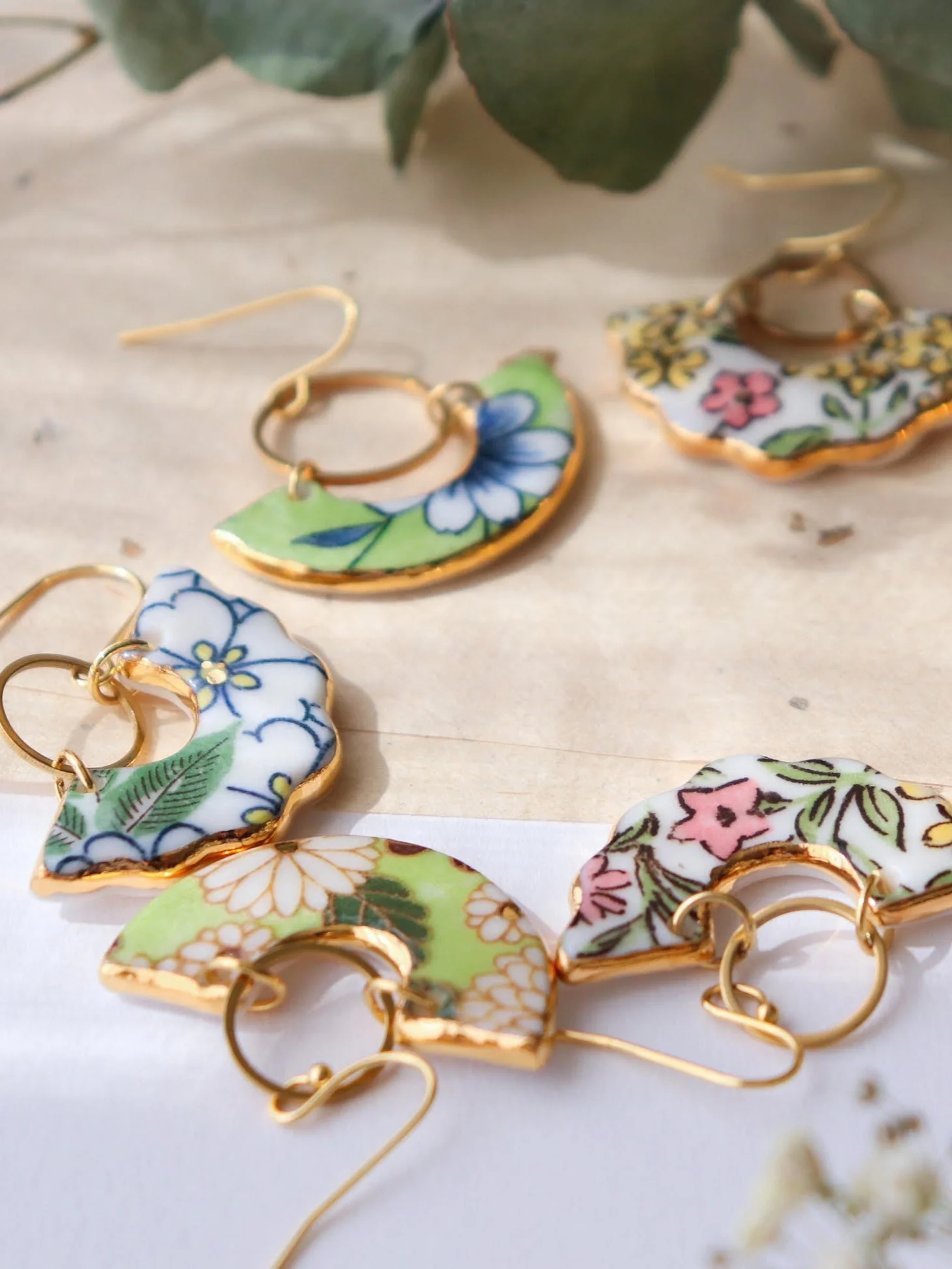 Boucles d'oreilles en céramique colorée avec motifs floraux assortis, encadrés de finition dorée.