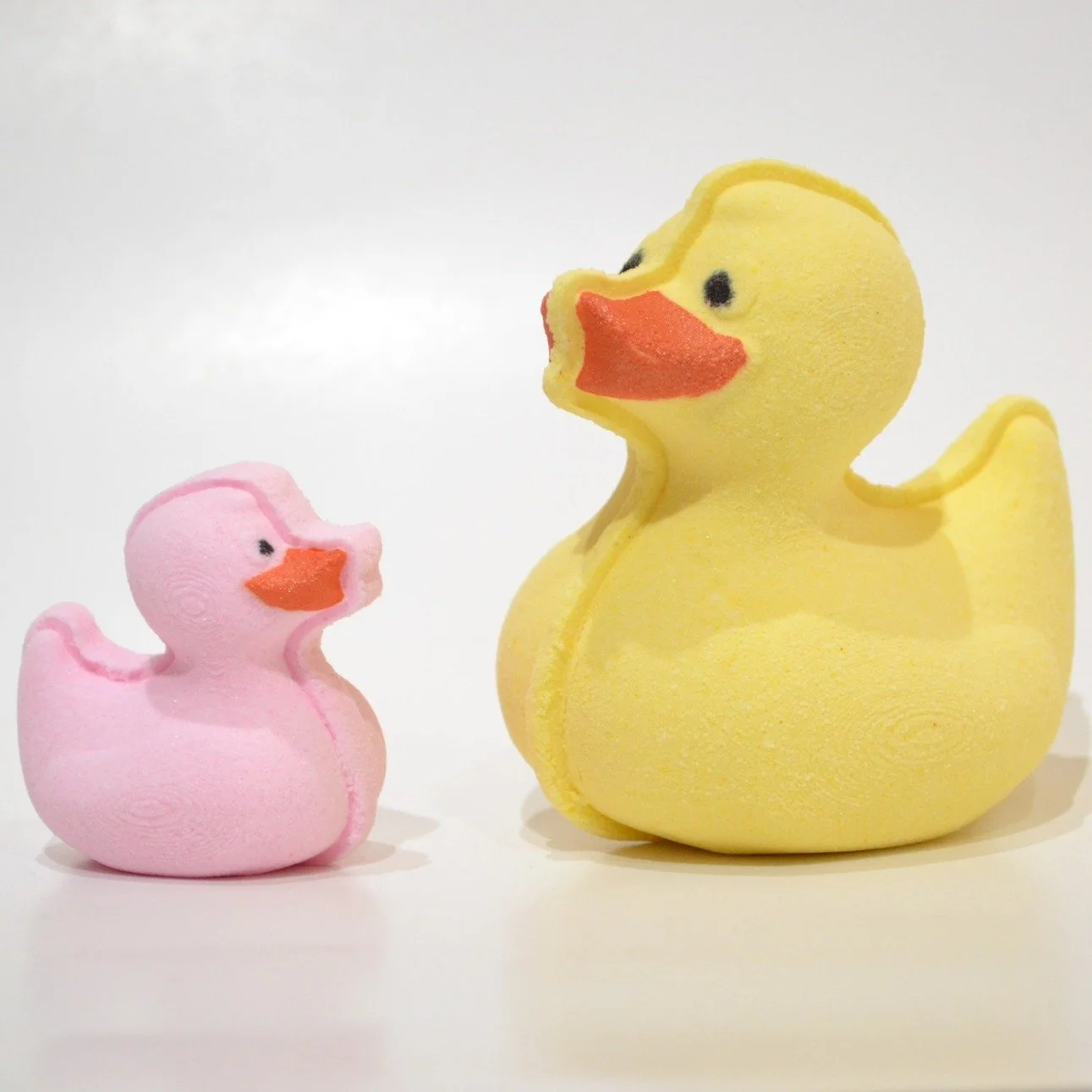 Deux canards en forme de bath bombs, un rose et un jaune, sur fond blanc.