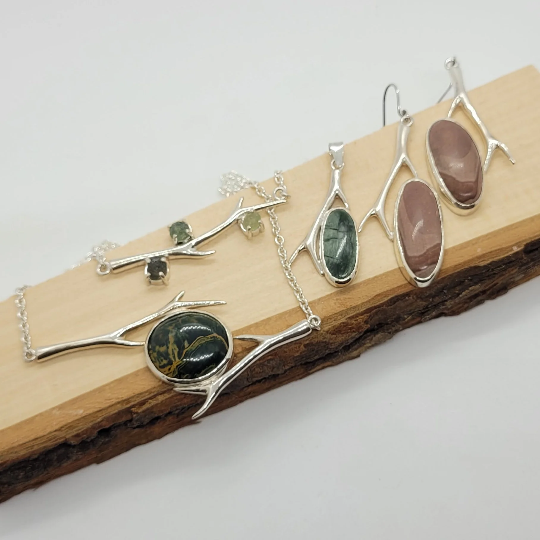 Une collection de bijoux en argent avec des pierres colorées, disposée sur une planche en bois