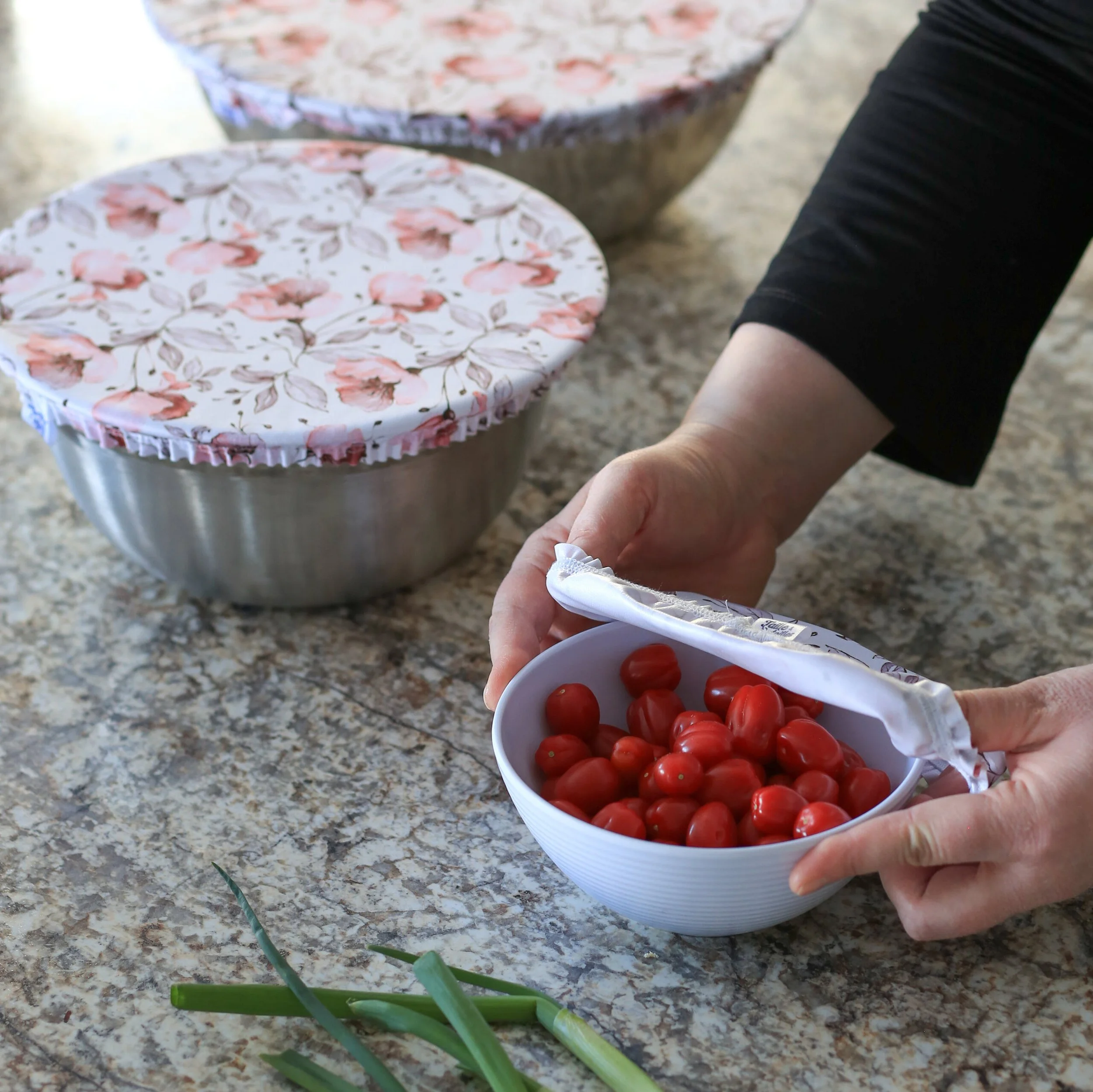 Une personne donne des tomates cerises rouge vif dans une tasse en plastique blanche.