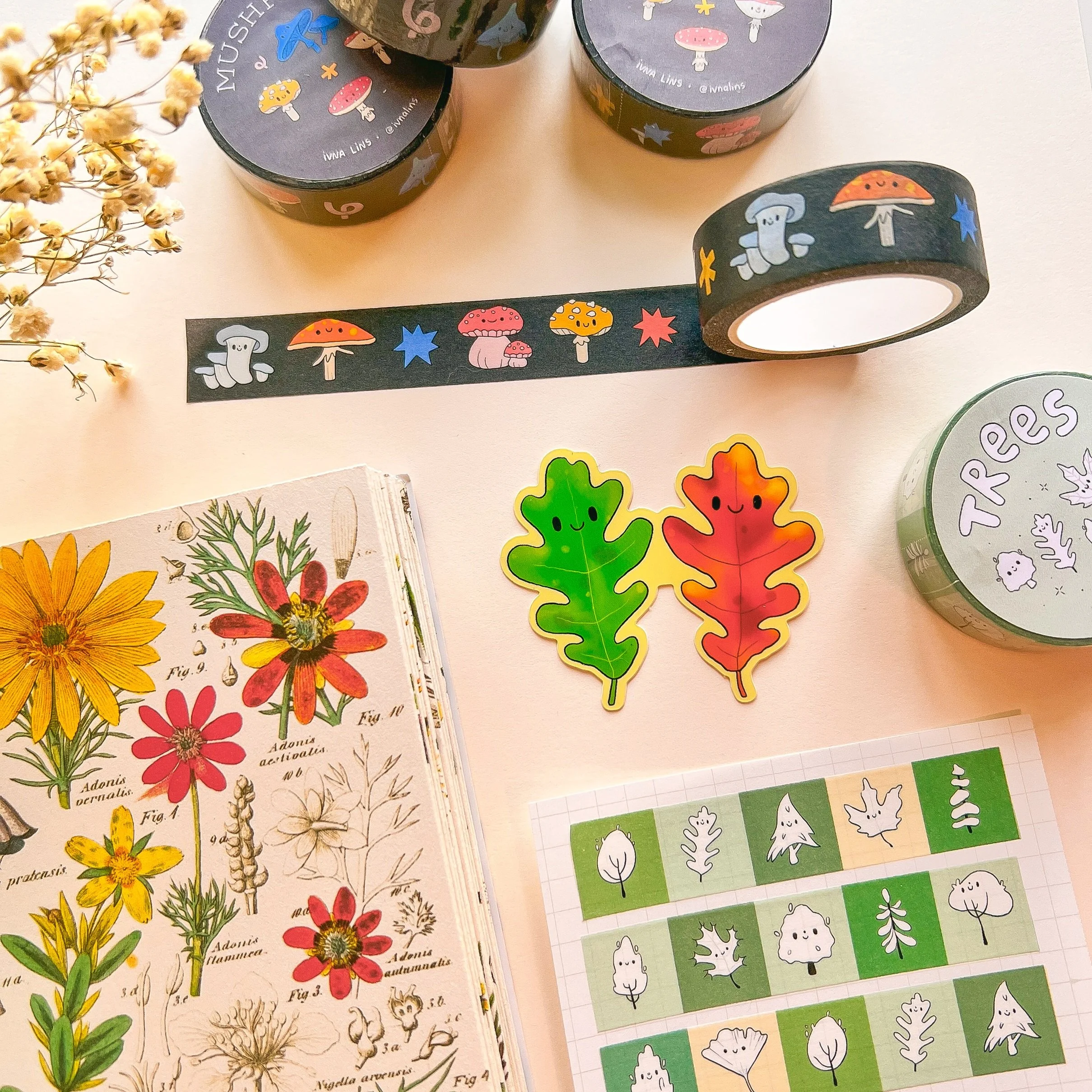 Décorations en washi tape avec des motifs de champignons, de feuilles, de petits personnages mignons et d'étoiles, ainsi que des illustrations de fleurs et de plantes séchées, sur une table
