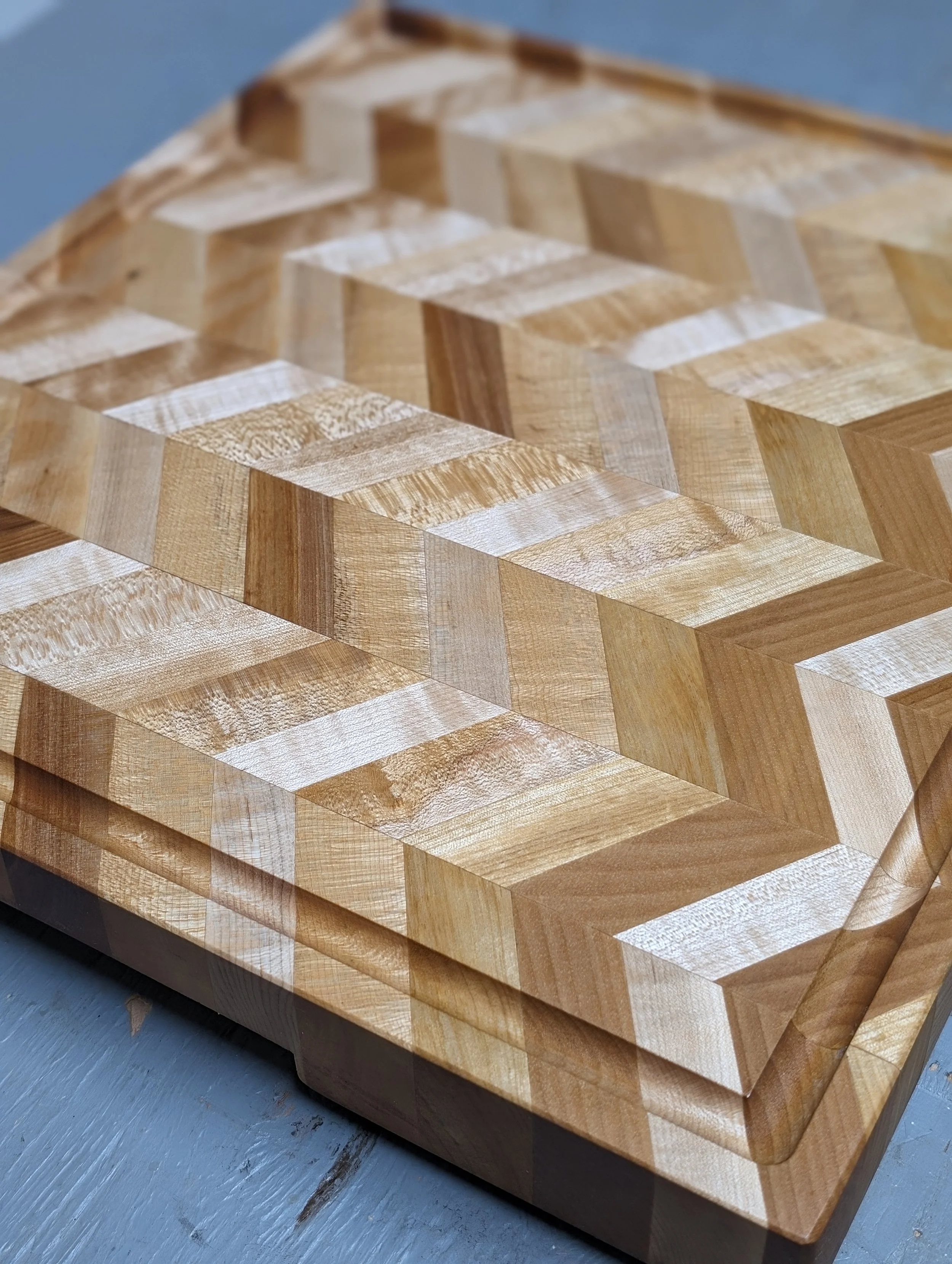 Une table en bois avec un motif géométrique en chevron composée de différentes teintes de bois naturelles.