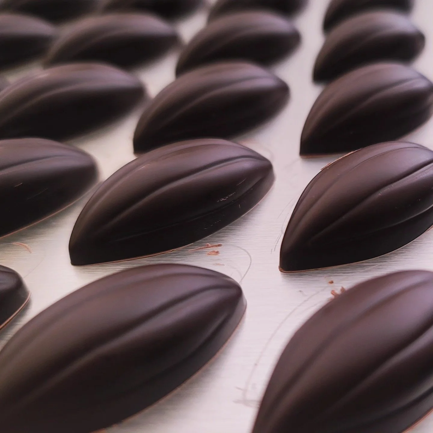 Gouttes de chocolat noir sur une plaque en acier inoxydable.