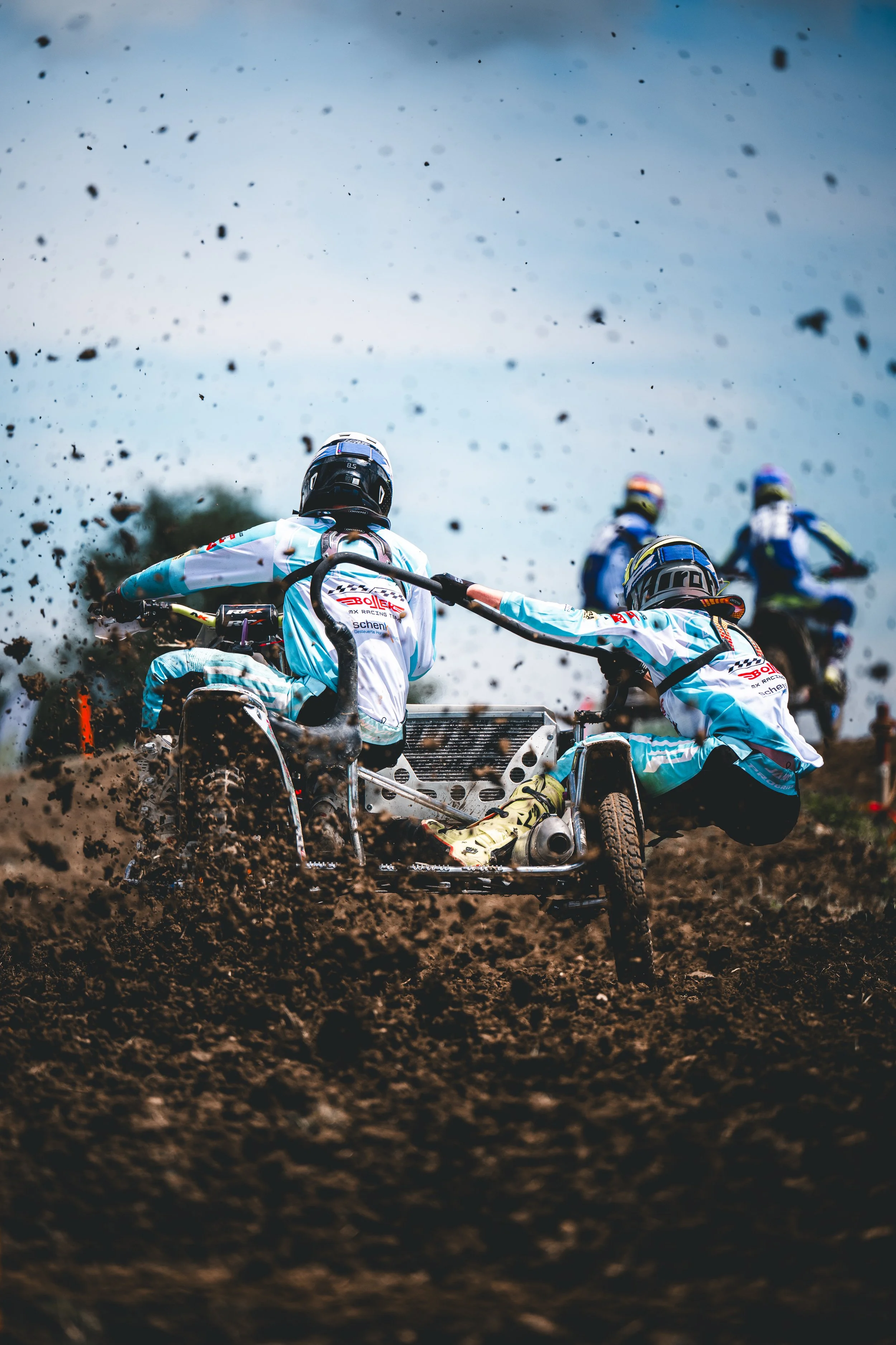 Dramatische Action-Aufnahme von hinten: Ein Motocross-Seitenwagenteam wirbelt beim Beschleunigen Schlamm und Dreck auf der Rennstrecke in Hünikon Thurgau auf.