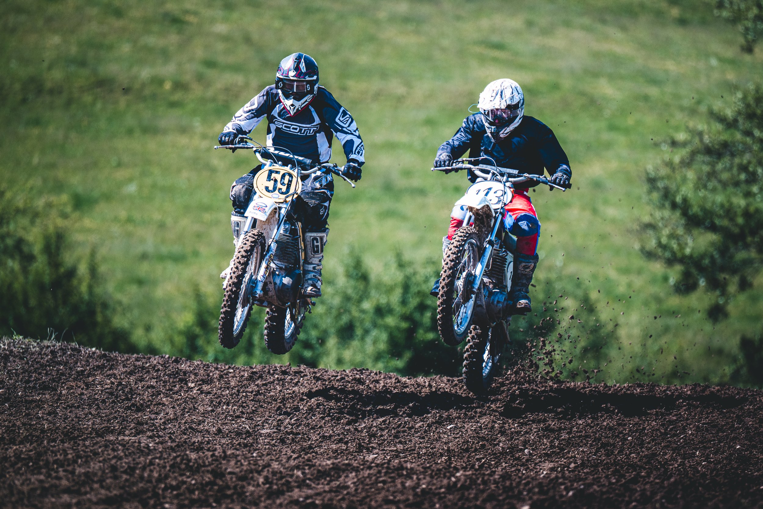 Zwei Motocross-Fahrer im synchronen Sprung über eine Kuppe beim SAM-Rennen in Hünikon (Thurgau), packendes Duell und Schweizer Action-Sportfotografie in Perfektion.