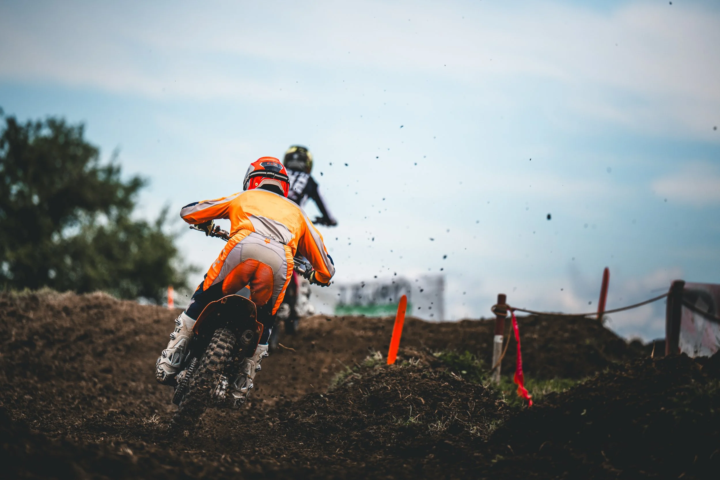 Ein Motocross-Fahrer in orangefarbener Gear bezwingt einen Hügel auf der SAM-Rennstrecke in Hünikon (Thurgau), stimmungsvolle Action-Aufnahme aus der Fahrerperspektive.