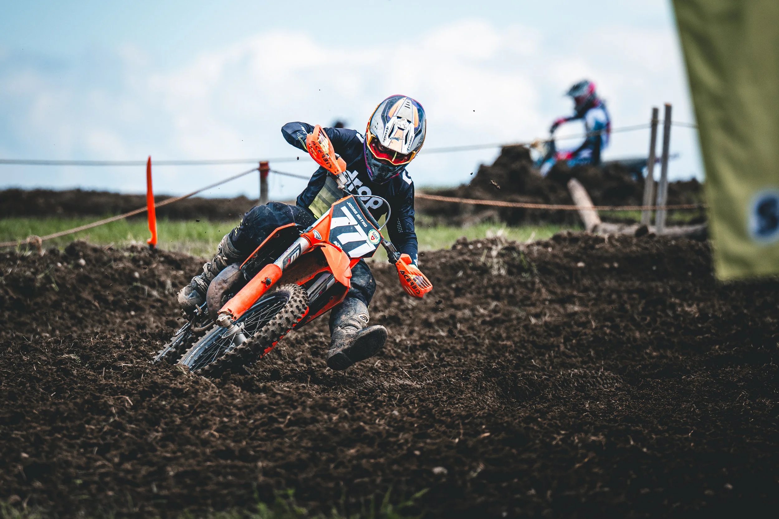 Ein KTM-Motocross-Fahrer mit der Startnummer 711 legt sich extrem tief in eine schlammige Kurve beim SAM-Rennen in Hünikon (Thurgau), messerscharf eingefrorene Schweizer Sport-Action.