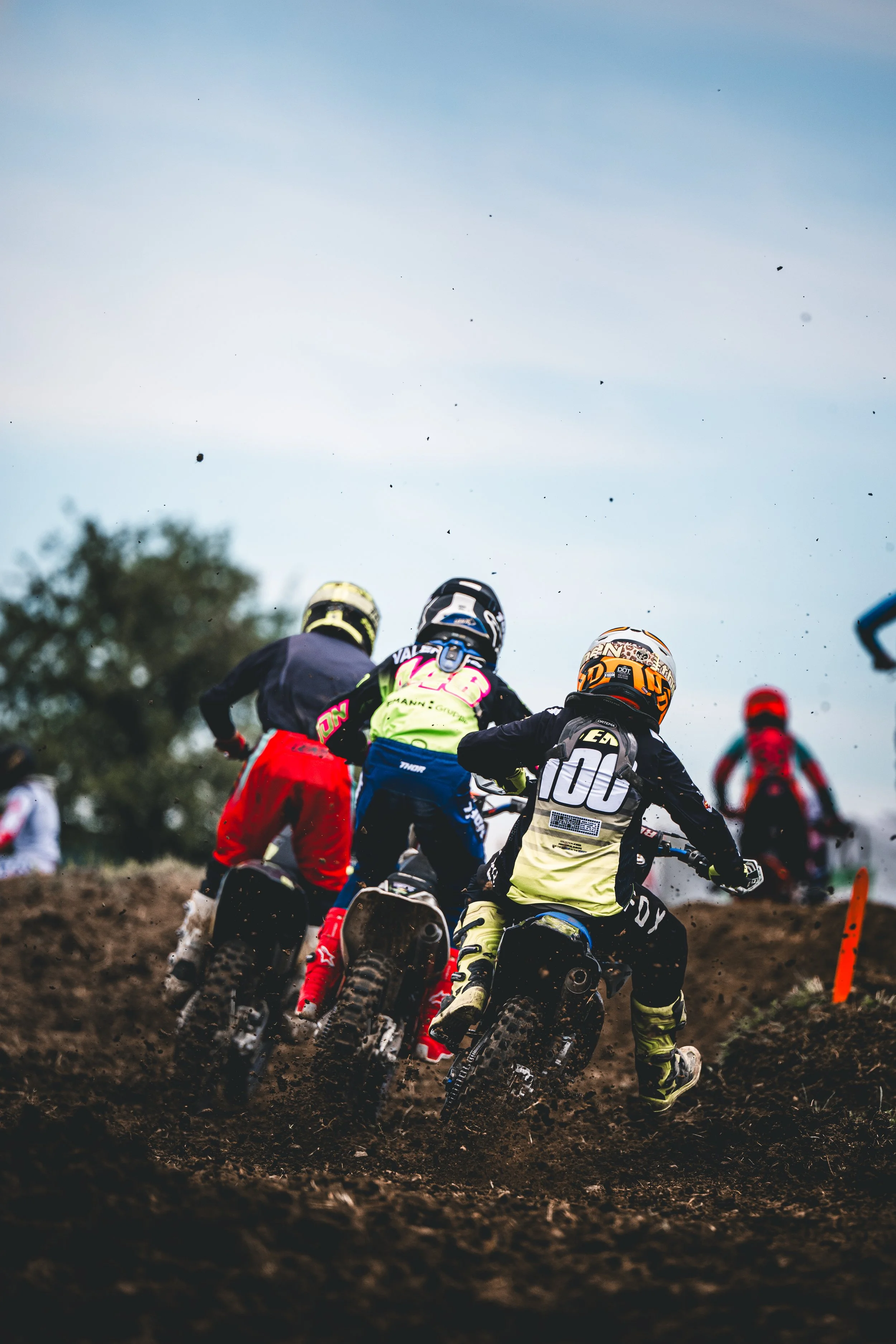 Actiongeladene Verfolgerperspektive einer Gruppe von Motocross-Fahrern beim Beschleunigen aus einer schlammigen Kurve auf der SAM-Rennstrecke in Hünikon (Thurgau), Ostschweiz.