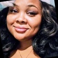 Close-up of a woman with curly black hair smiling at the camera