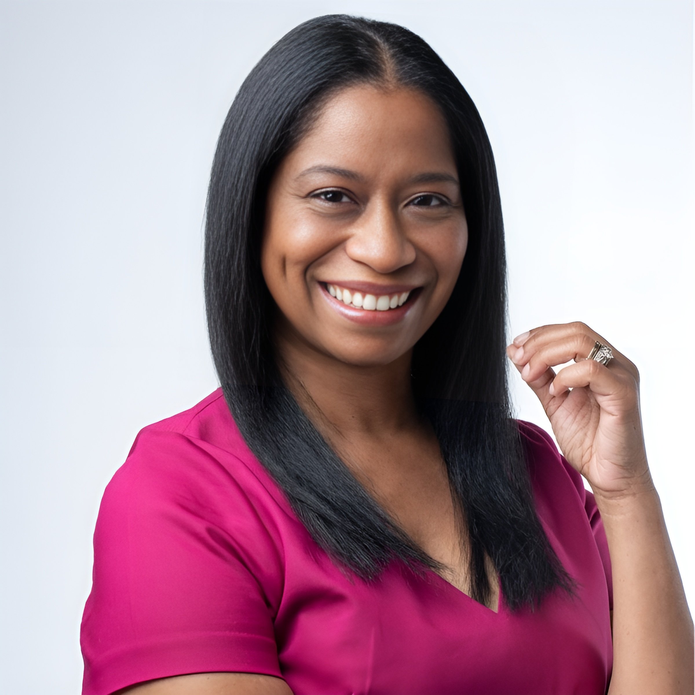 A woman with long black hair, smiling, wearing a bright pink top, posing against a plain white background.