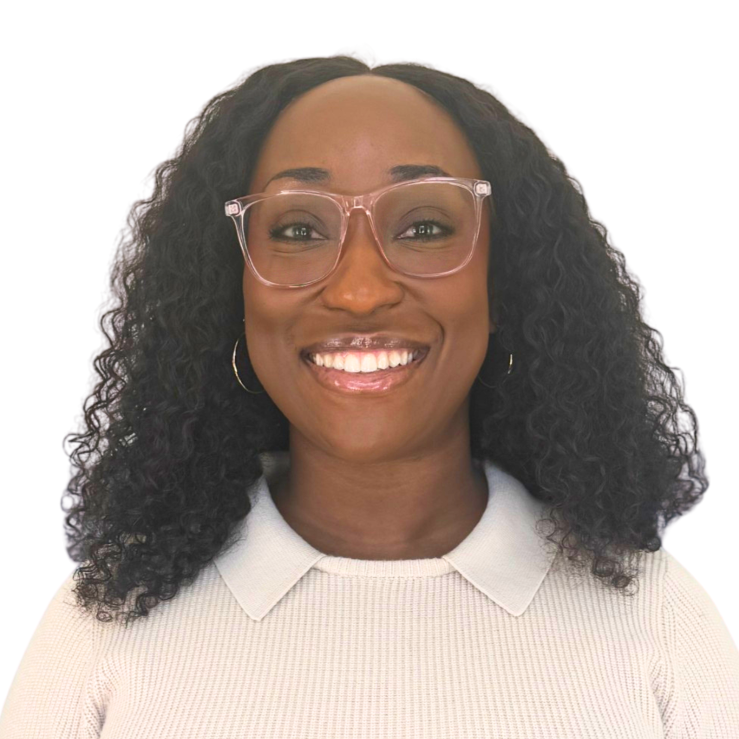 Close-up of a smiling woman with dark, curly hair wearing clear glasses and a light-colored sweater against a plain background.