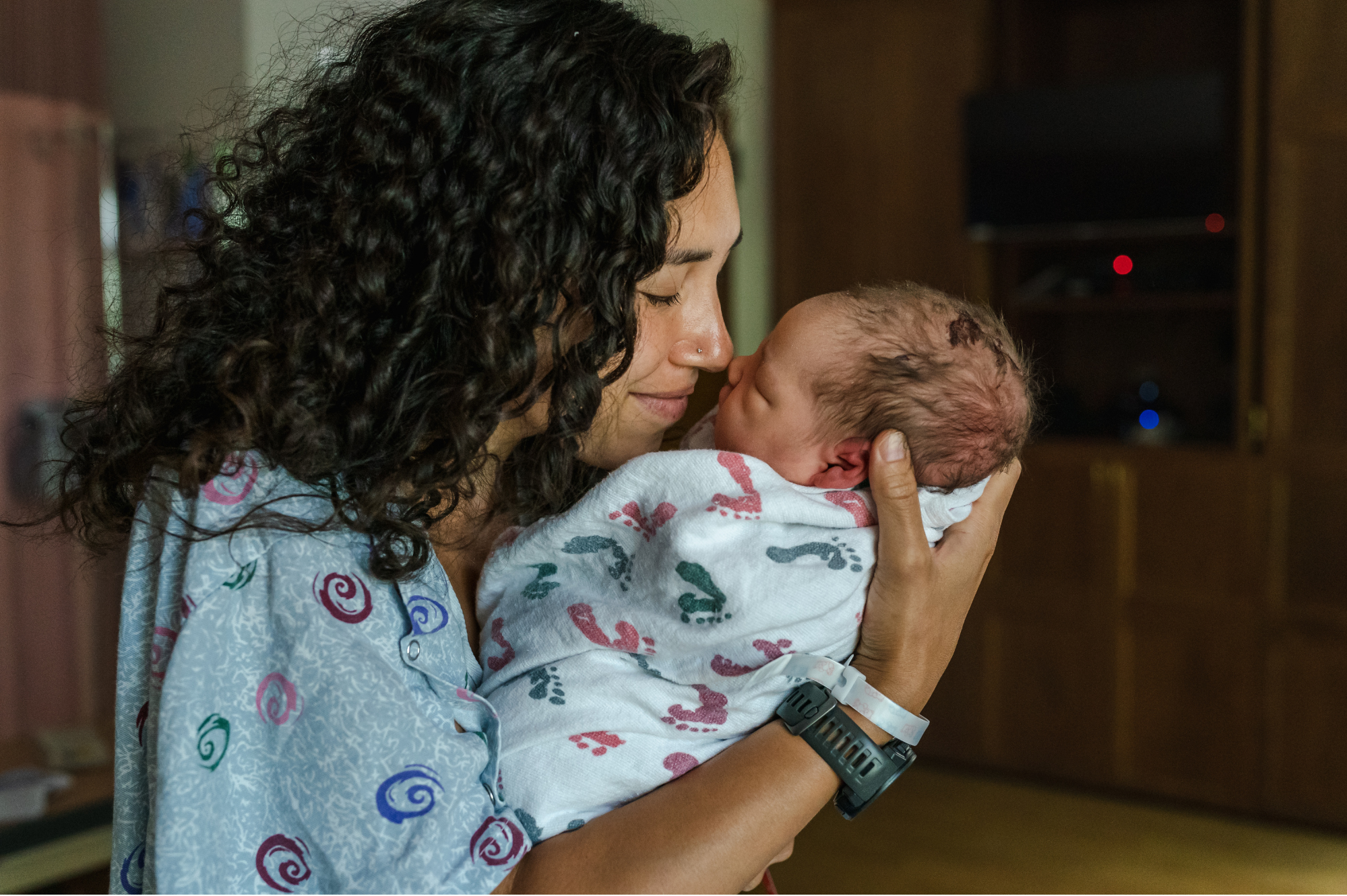 A young mother lovingly holds her newborn baby, reflecting the care and support provided through Sarah's House.
