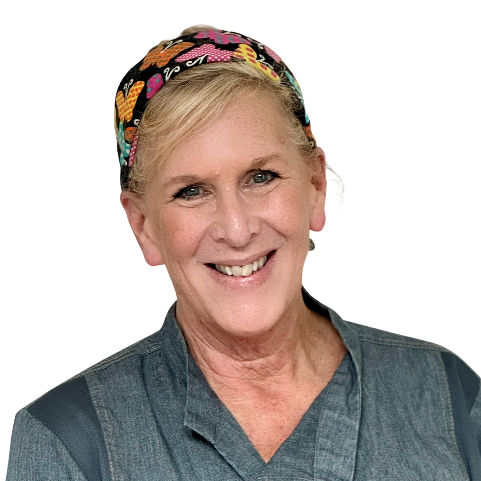 A smiling woman with blue eyes wearing a colorful headscarf and a gray uniform with black accents.