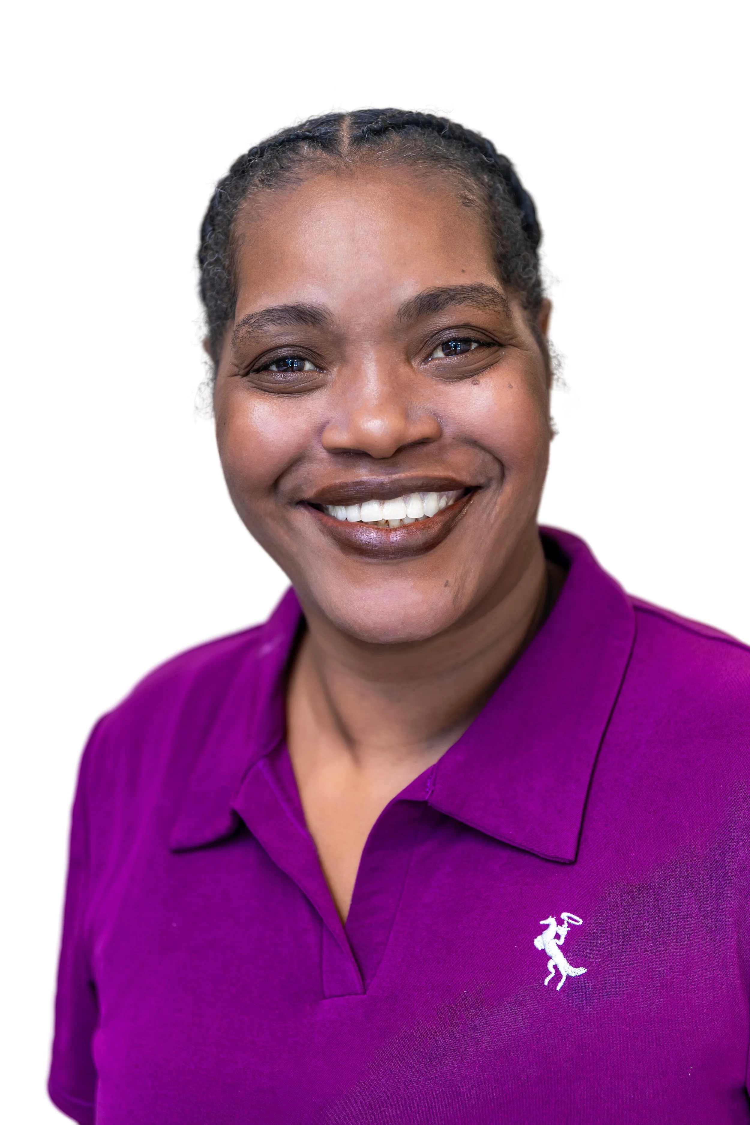 Smiling woman wearing glasses, green T-shirt, and a black lanyard in front of a white and blue wall.