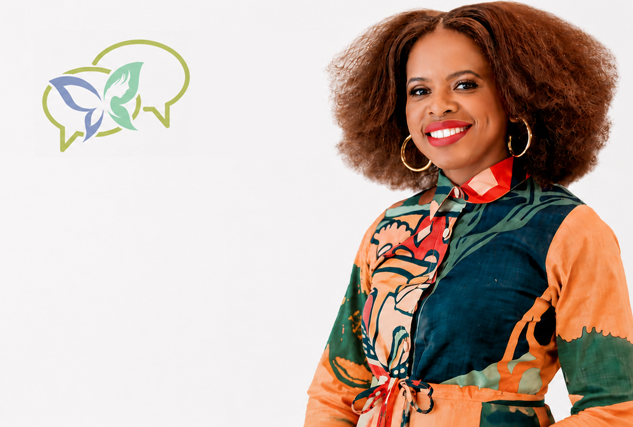 A woman with curly brown hair, gold hoop earrings, and bright red lipstick, smiling while wearing a colorful, patterned blouse with orange, green, and navy blue colors, against a plain light background. There is a speech bubble logo with a butterfly inside on the left side.