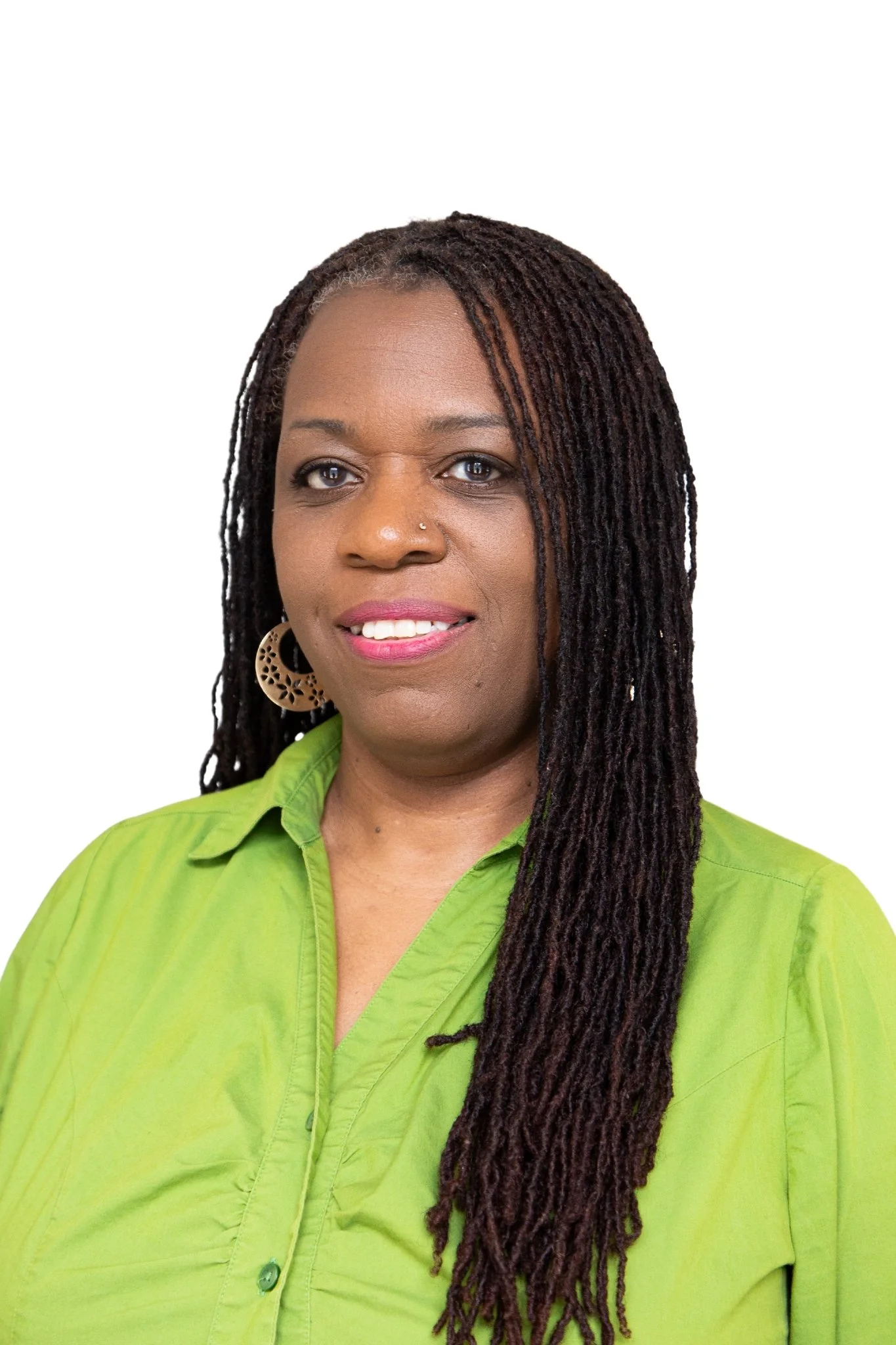 Close-up of an African American woman with dreadlocks, wearing a bright green shirt, and large earrings, smiling against a plain background.