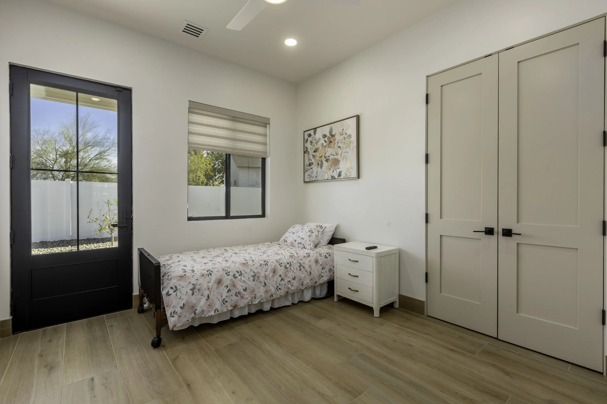 Bedroom with a bed, a bedside table, a closet, and a window showing an outdoor scene.