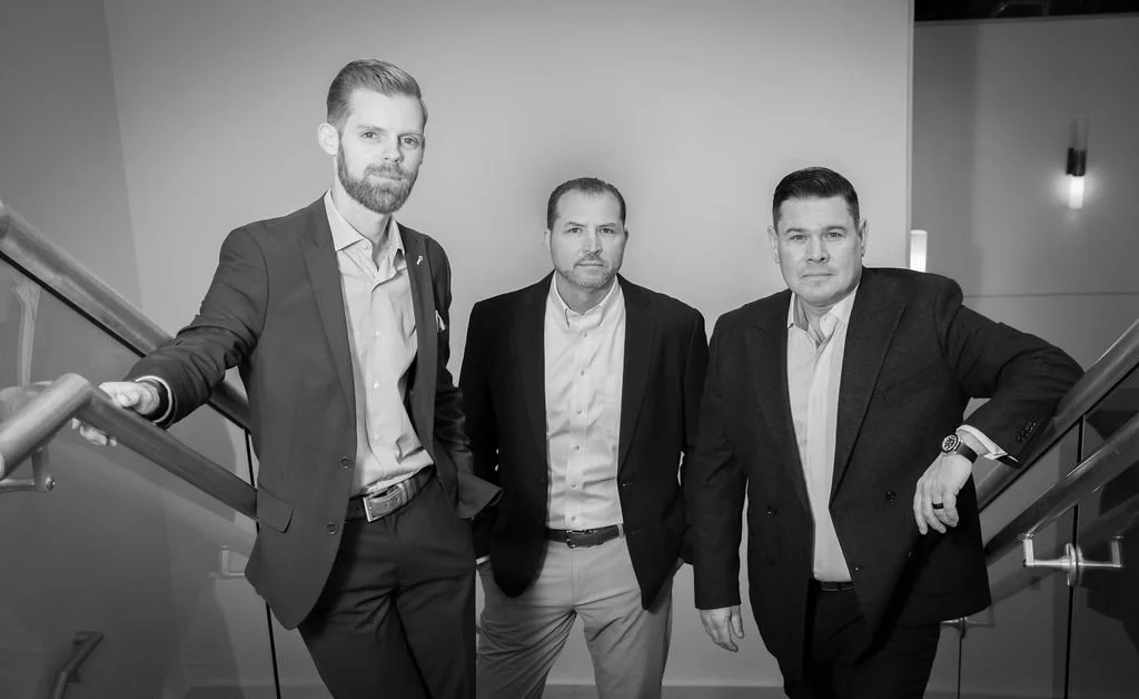 Three men in suits standing on a staircase.